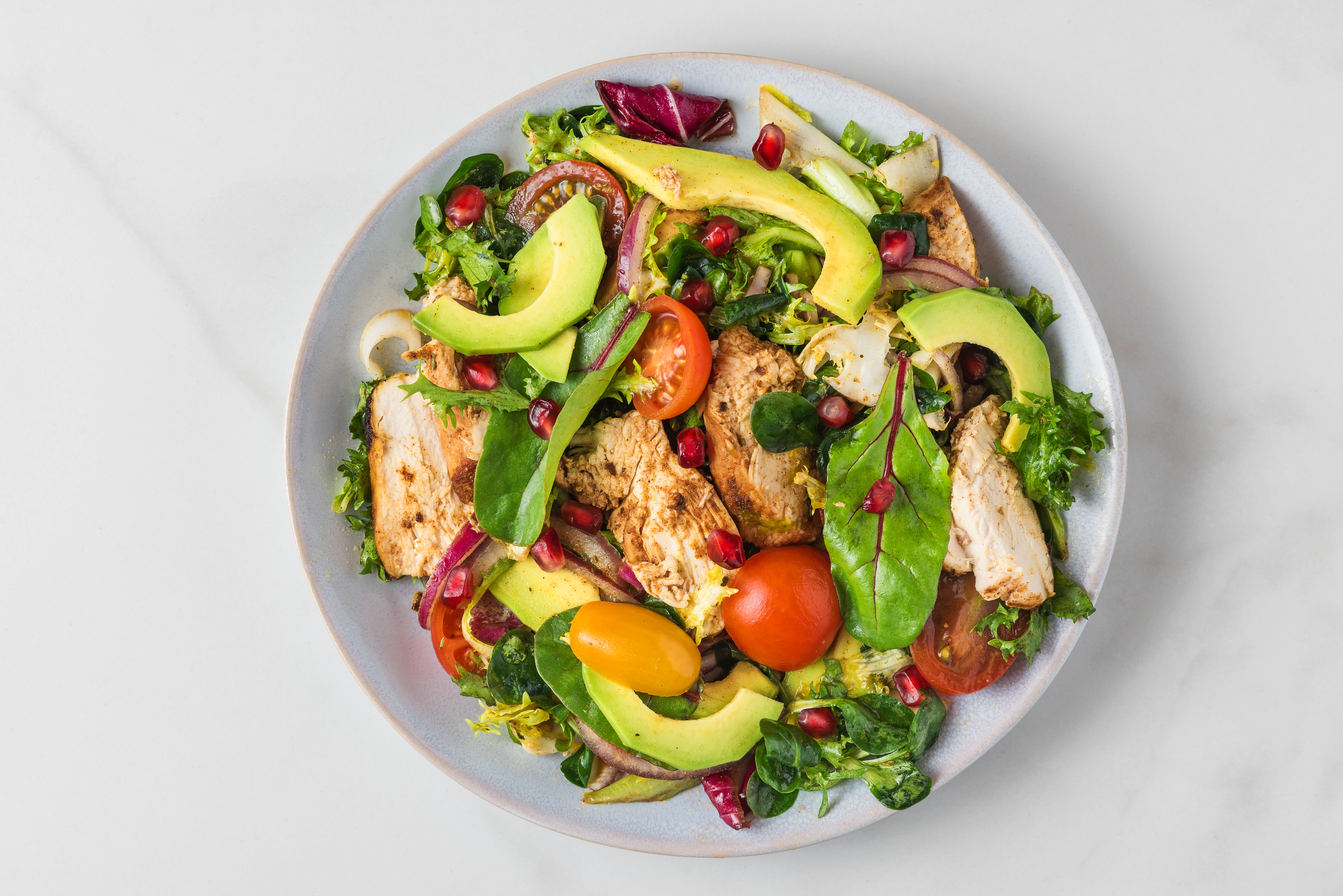 Ensalada con pechuga de pollo dorada, frutos secos, aguacate y tocineta