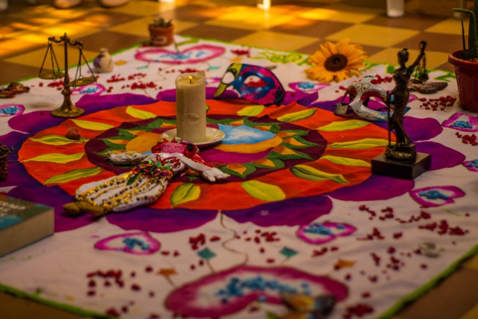 imagen de una sábana con elementos varios como fotos, velas y objetos simbólicos