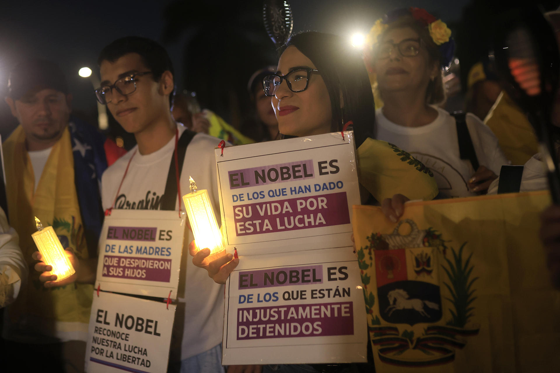 AME6424. CIUDAD DE PANAMÁ (PANAMÁ), 06/12/2025.- Personas sostienen carteles durante la marcha "por la paz y la libertad" en Venezuela este sábado, en Ciudad de Panamá (Panamá). Decenas de venezolanos se sumaron en Panamá a las marchas globales "por la paz y la libertad" en Venezuela convocadas el jueves por la líder opositora y exdiputada del país sudamericano María Corina Machado. EFE/ Bienvenido Velasco