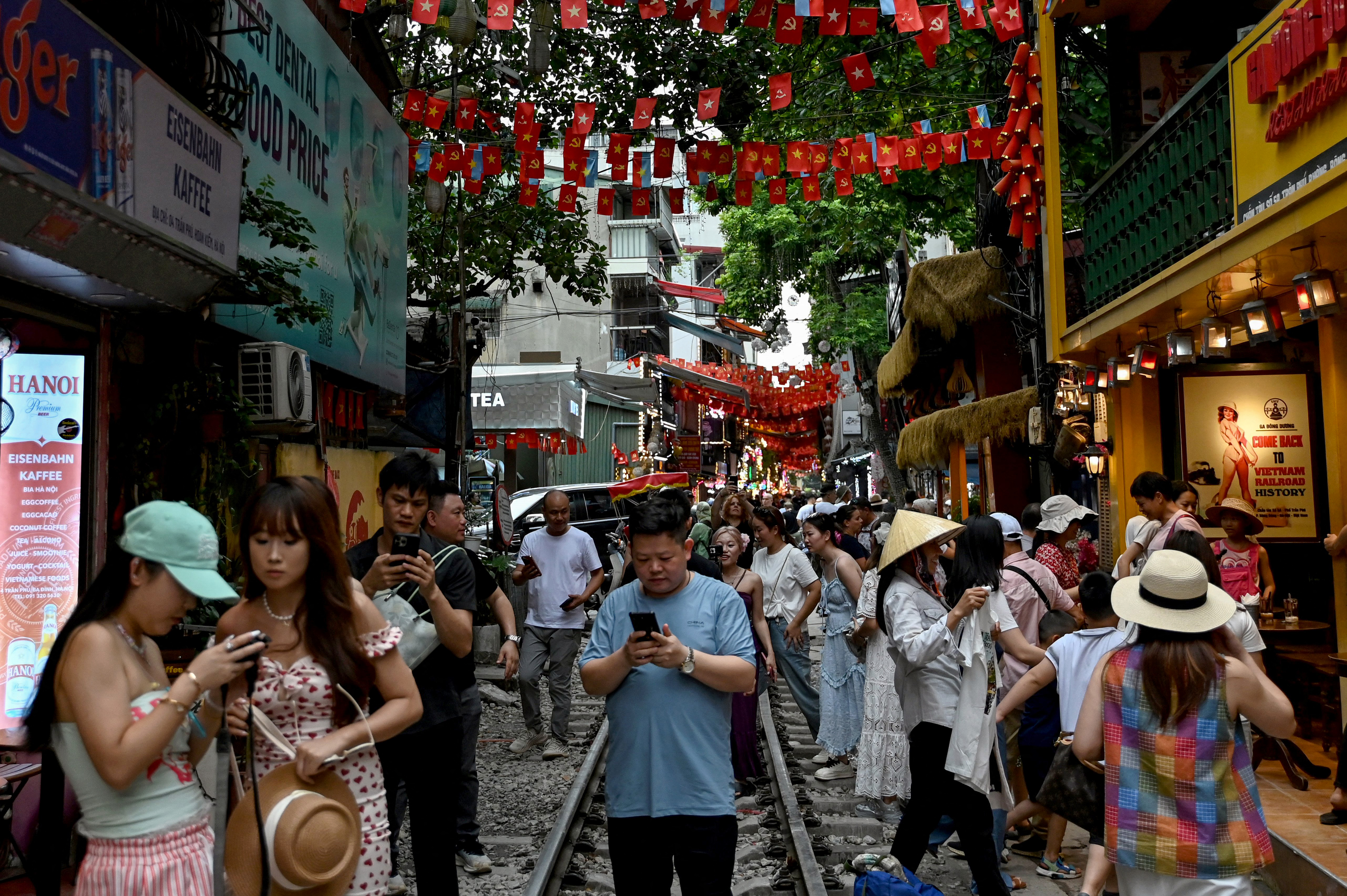 This photo taken on August 18, 2025 shows tourists walking along a railway track between cafe terraces in central Hanoi.