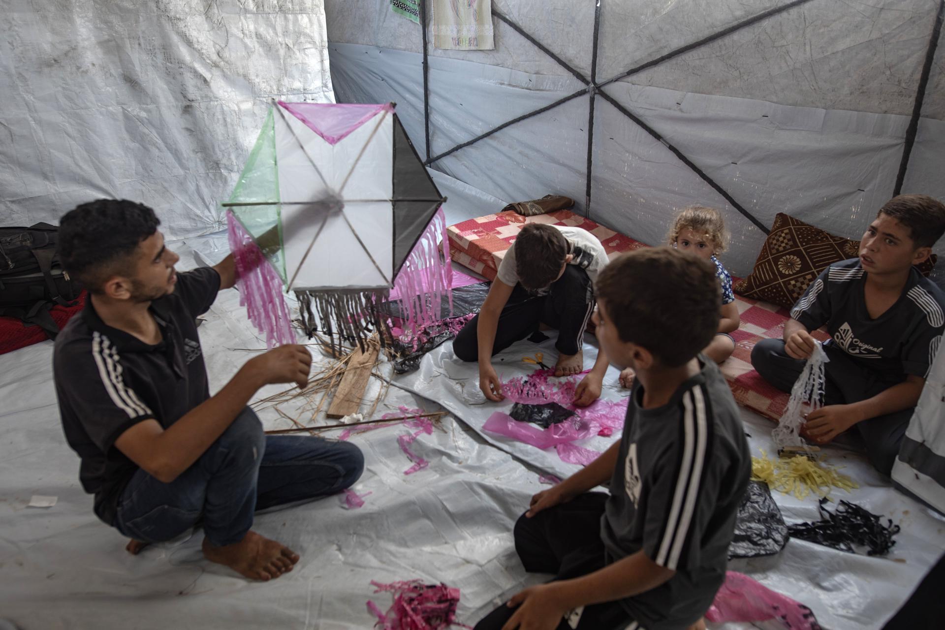 Khan Younis (-), 27/08/2026.- Palestinian youths craft kites at al-Mawasi camp, near Khan Younis, southern Gaza Strip, 27 August 2026. Without safe places to play, displaced Palestinian children make kites from basic materials to cope with displacement and the heat inside their tents, and find a moment of relief. However, recent warnings from the Israeli military against kite-flying have turned a harmless children’s game into another source of fear and anxiety inside the displacement camps. EFE/EPA/HAITHAM IMAD
