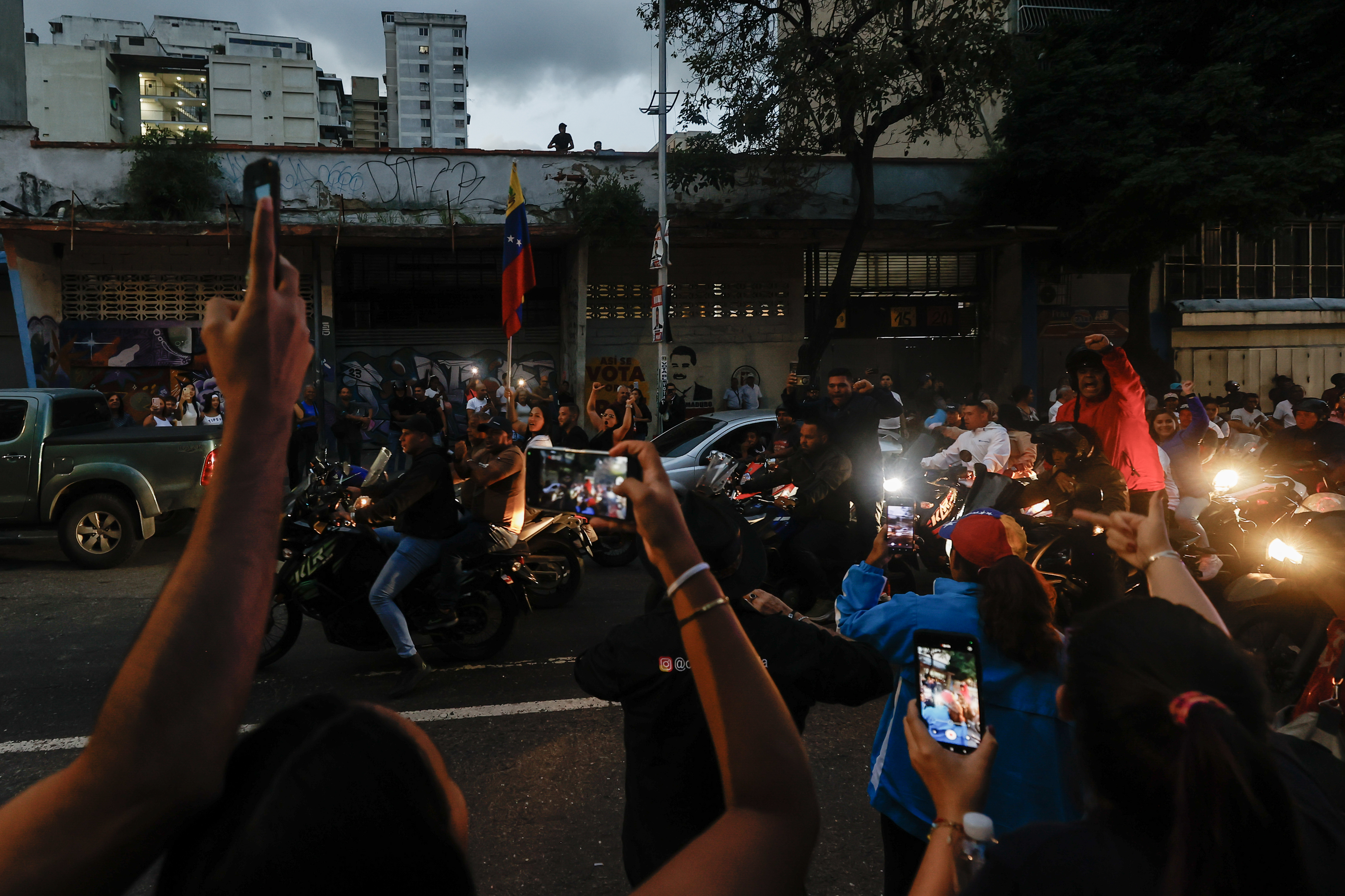 AME5914. CARACAS (VENEZUELA), 28/07/2024.- Seguidores del presidente de Venezuela y candidato a la reelección, Nicolás Maduro, gritan consignas en una caravana de motocicletas este domingo, en Caracas (Venezuela). Varias decenas de motorizados que se identificaron como chavistas llegaron a un centro de votación en Caracas, donde se encontraban testigos opositores y ciudadanos que esperaban el comienzo del escrutinio de las elecciones presidenciales de este domingo, lo que dio lugar a una confrontación que acabó a golpes, ante la mirada impasible de los policías, que no intervinieron para detener la pelea. EFE/ Henry Chirinos