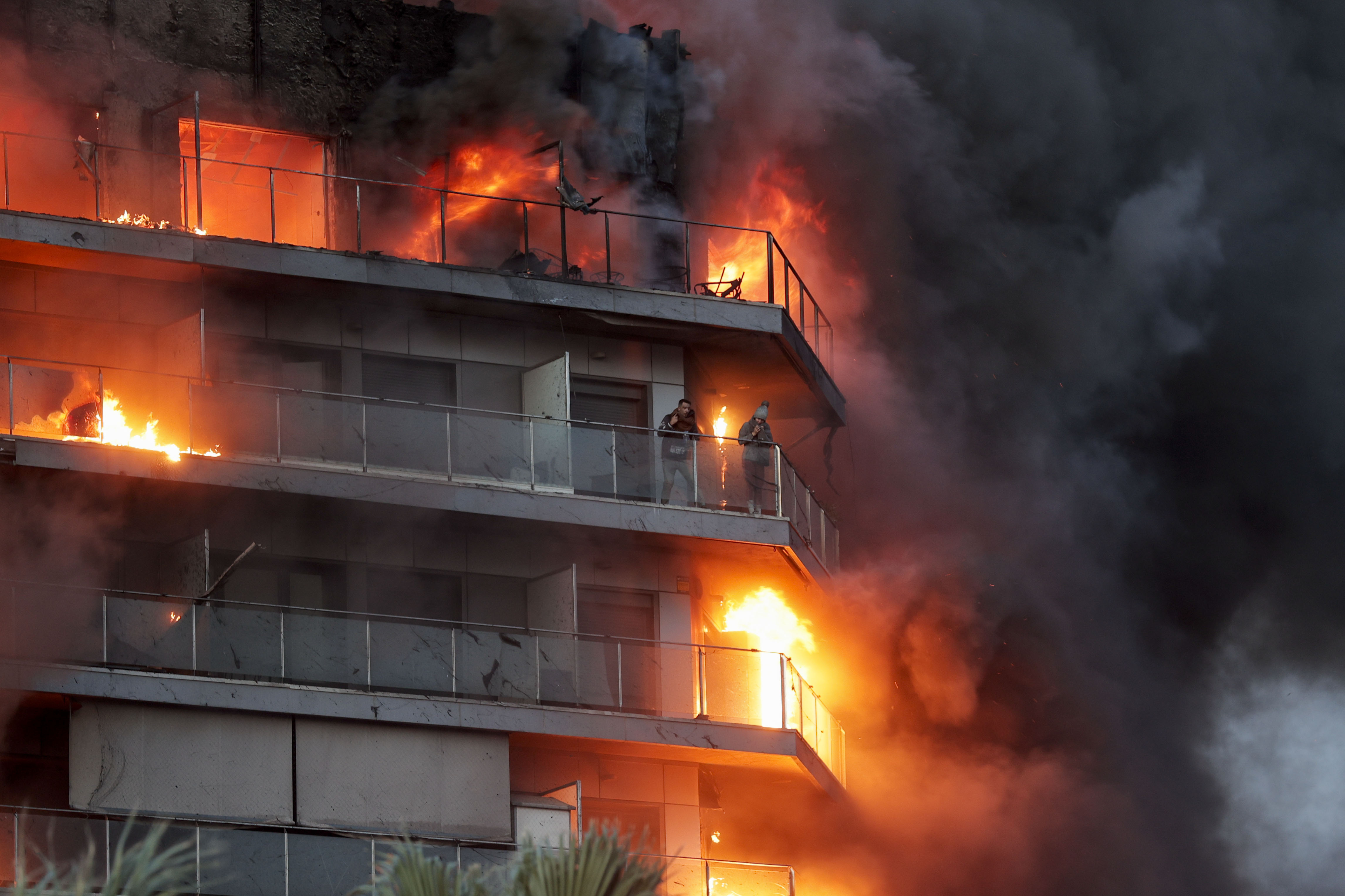 GRAFCVA8510. VALENCIA, 22/02/2024.- Dos personas aguardan en el balcón a ser rescatadas en el incendio declarado sobre las cinco y media de esta tarde en un quinto piso de un edificio de viviendas de València que ha afectado totalmente al inmueble y se ha propagado a otro anexo, y los bomberos intentan aún rescatar a vecinos desde los balcones. EFE/Manuel Bruque