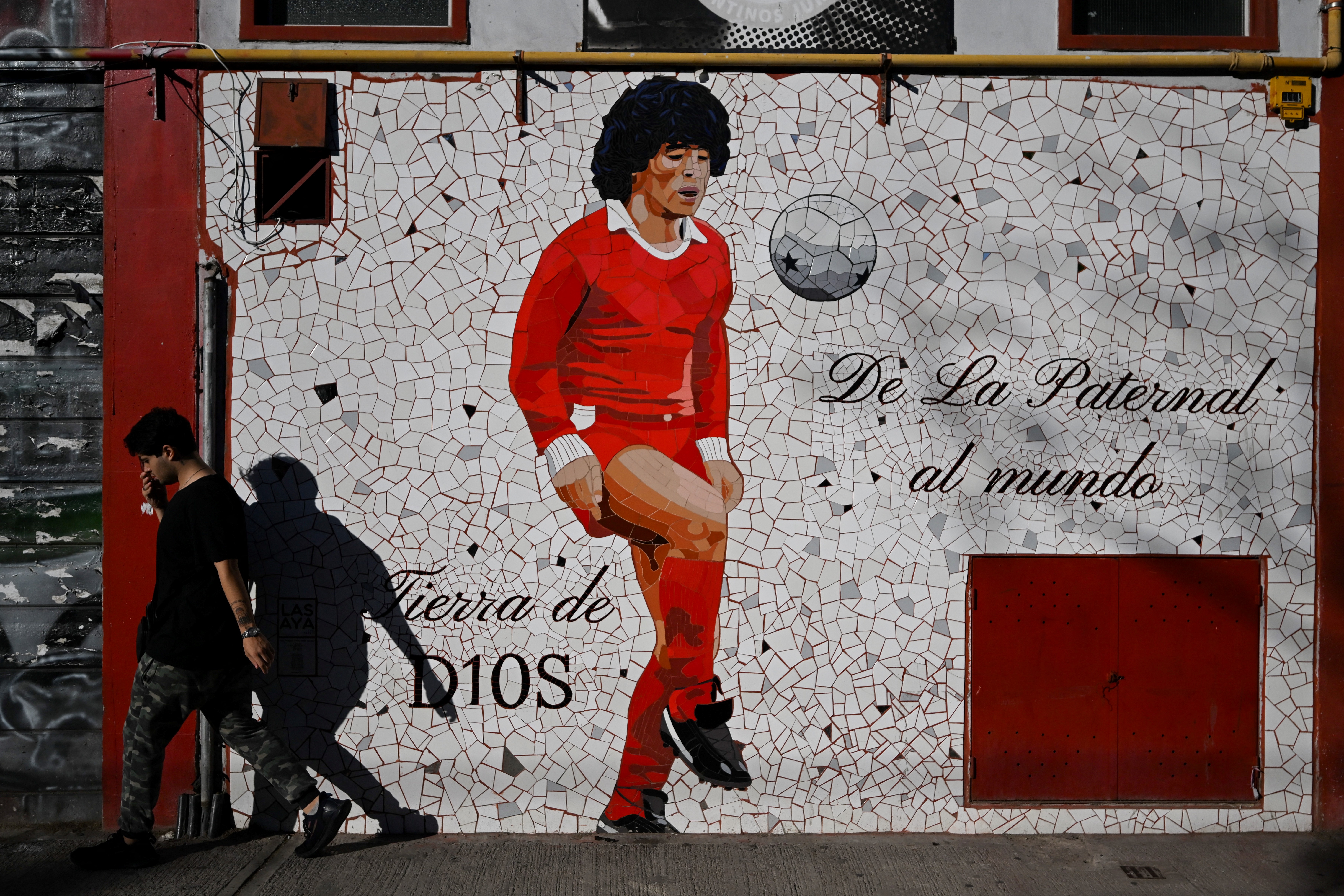 TOPSHOT - A man walks past a mural depicting late Argentine football legend Diego Maradona outside the Diego Armando Maradona stadium, home of the Argentine football team Argentinos Juniors at La Paternal neighborhood in Buenos Aires on March 10, 2025.