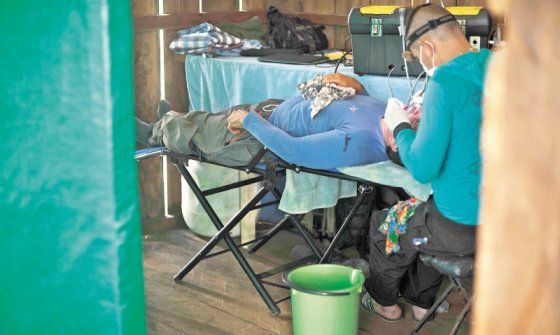 Un guerrillero odontólogo interviene a uno de sus compañeros en la enfermería construida en el campamento de los llanos del Yarí, en Caquetá.  / / Óscar Pérez