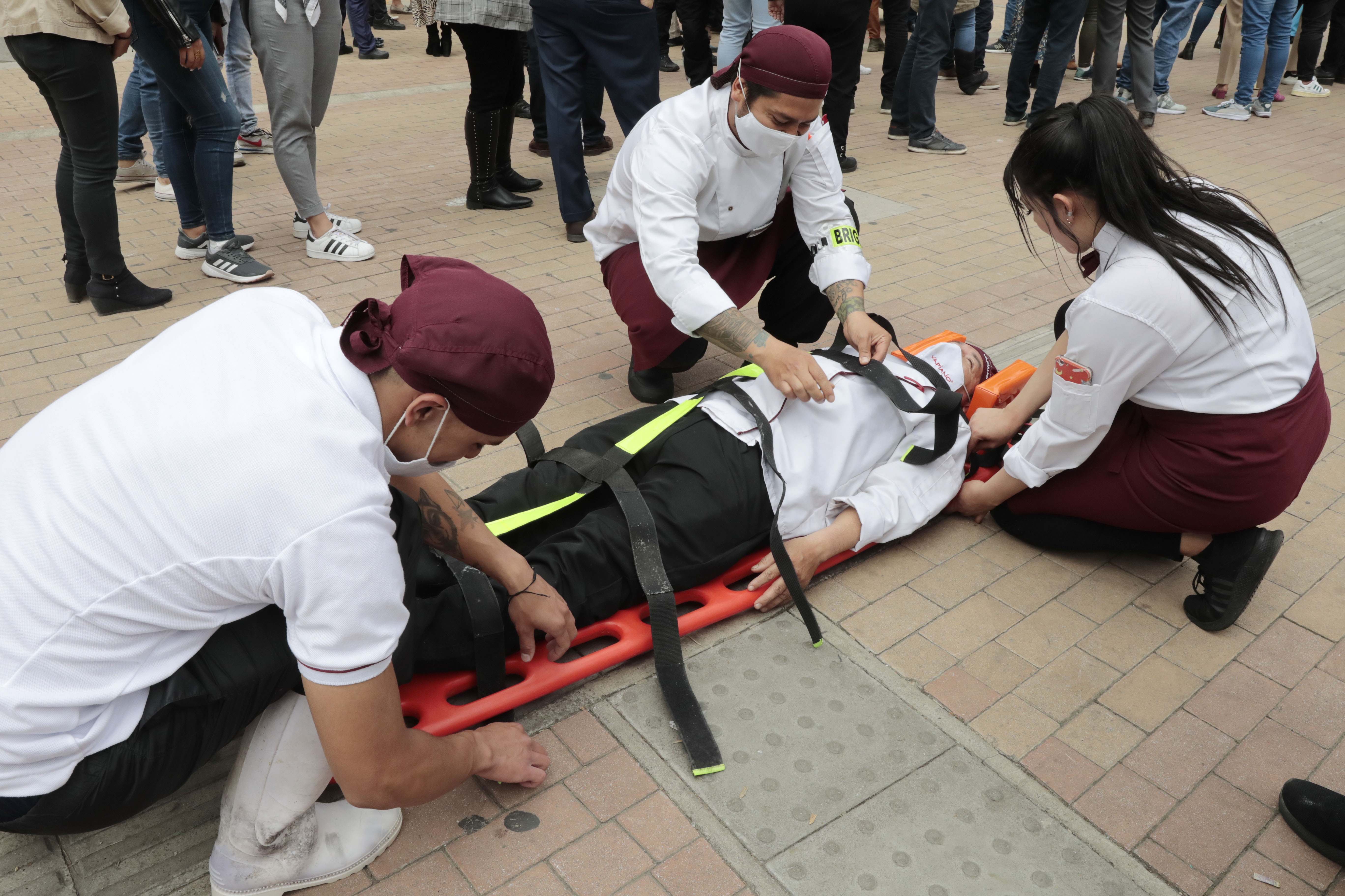AME2093. BOGOTÁ (COLOMBIA), 04/10/2022.- Un grupo de personas recrea el levantamiento de un paciente en camilla durante un simulacro de evacuación para medir la capacidad de respuesta ante un eventual terremoto o situación de emergencia, hoy, en Bogotá (Colombia). El distrito convocó este martes a los bogotanos a participar de un simulacro de evacuación, enfocado en las reacciones acordes a situaciones de riesgo, catástrofes naturales y aglomeraciones. EFE/ Carlos Ortega