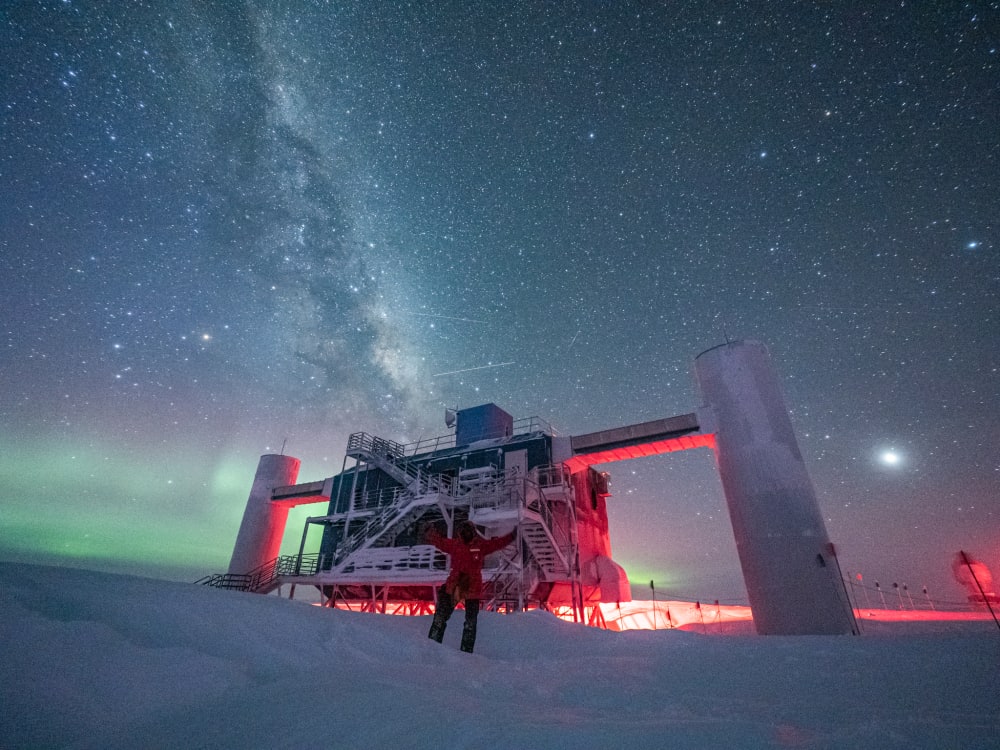 El telescopio IceCube, ubicado en el Polo Sur, con auroras y la Vía Láctea de fondo.