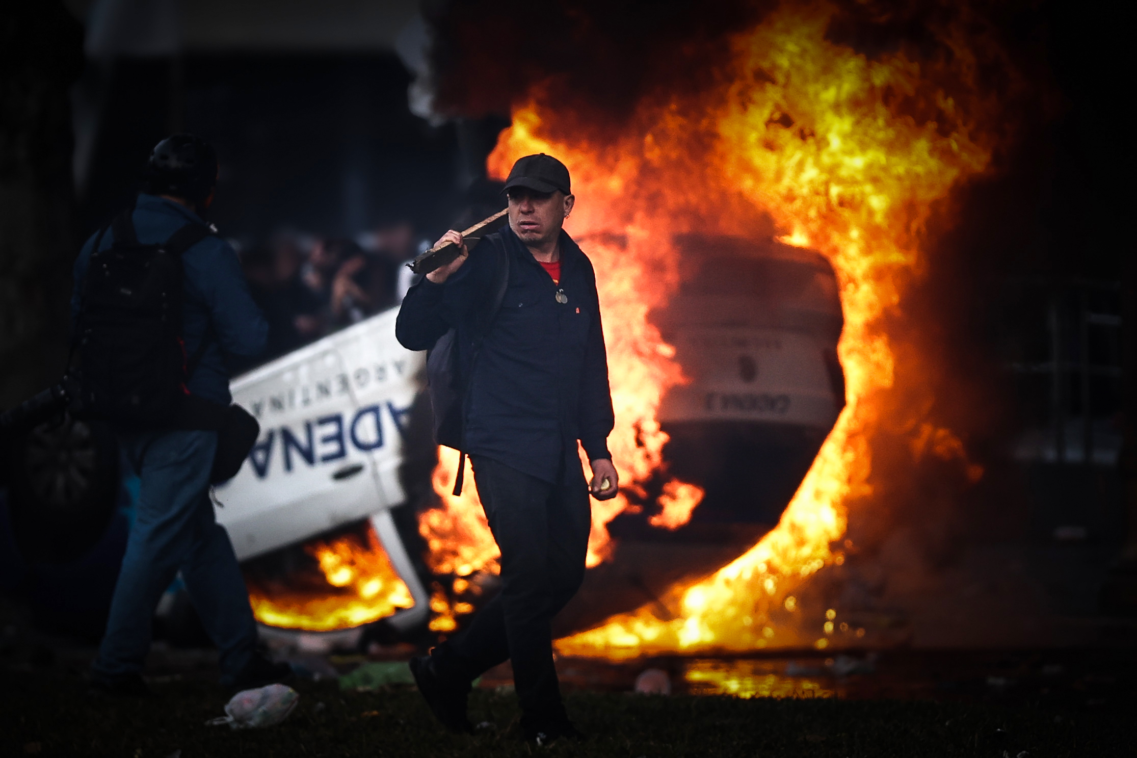 -FOTODELDÍA- AME3687. BUENOS AIRES (ARGENTINA), 12/06/2024.- Un hombre es visto caminar frente a una carro en llamas en una protesta a las afueras del senado durante un debate este miércoles, en Buenos Aires (Argentina). Manifestantes y policías protagonizan un choque este miércoles a las puertas del Senado de Argentina mientras la cámara legislativa debate la ley de Bases, el proyecto estrella del Gobierno, con el que el presidente Javier Milei pretende implementar un paquete de reformas económicas de gran calado. EFE/ Juan Ignacio Roncoroni