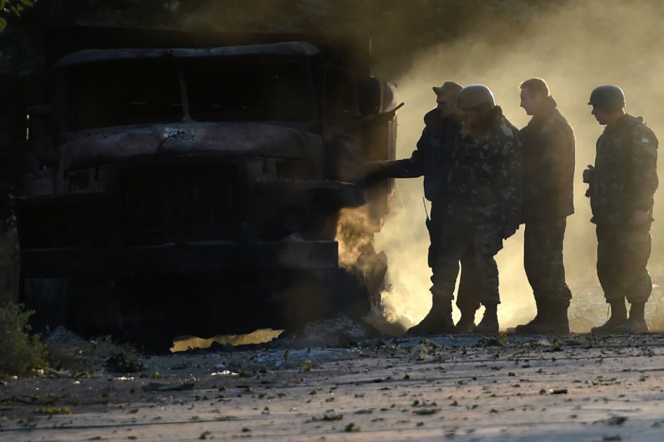 Soldados del ejercito ucraniano revisan uno de los camiones quemados durante el ataque
