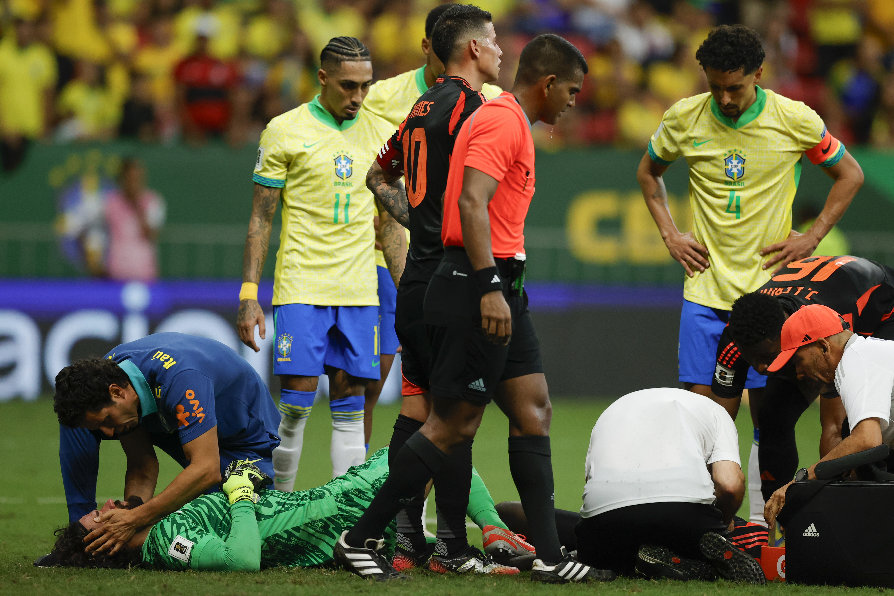 AME1064. BRASILIA (BRASIL), 20/03/2025.- Alisson Becker (i) de Brasil y Davinson Sánchez de Colombia son atendidos tras un golpe de cabezas este jueves, en un partido de las eliminatorias sudamericanas al Mundial de 2026 entre las selecciones de Brasil y Colombia, en el estadio Arena BRB Mané Garrincha, en Brasilia (Brasil). EFE/ Andre Coelho