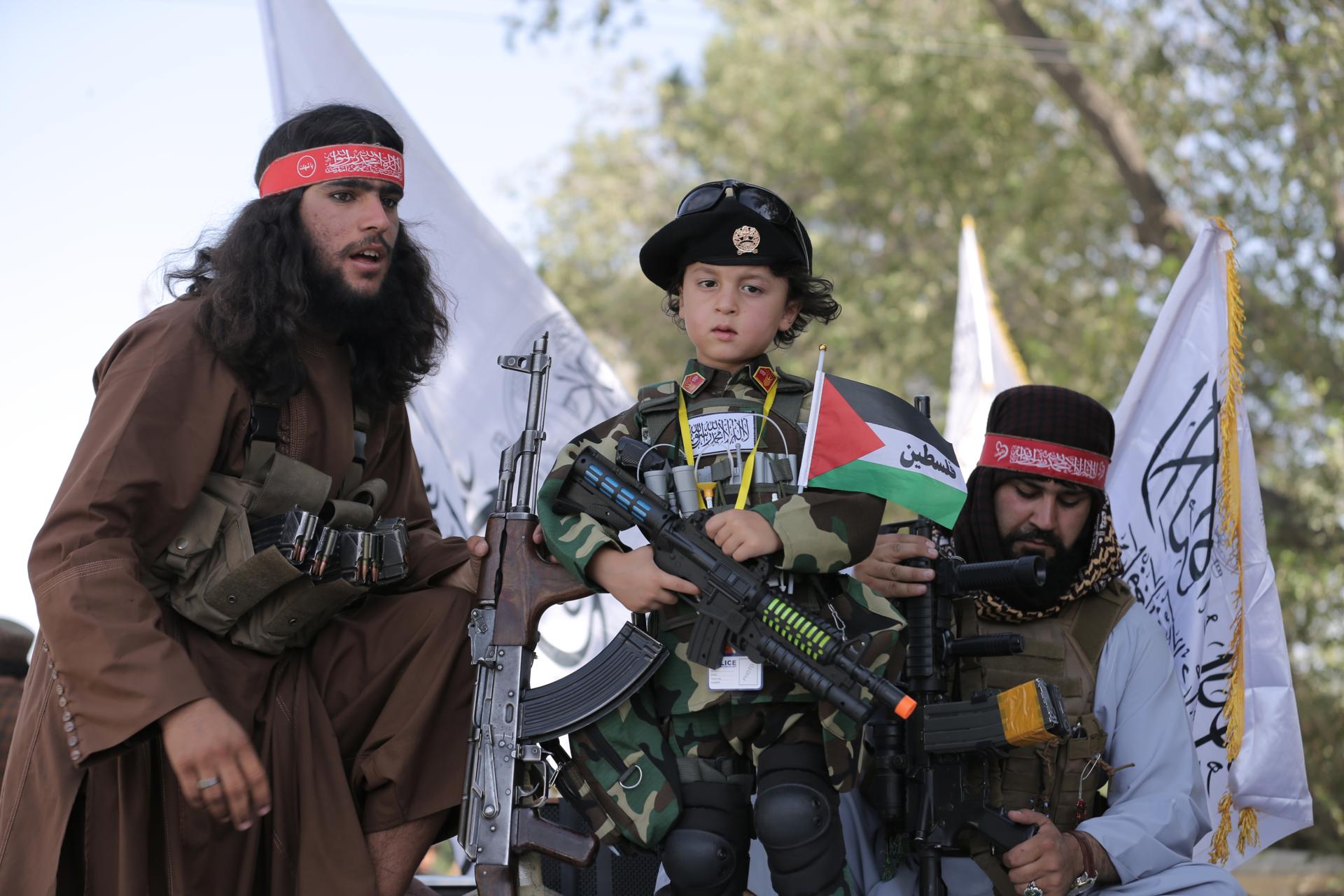 Kabul (Afghanistan), 15/08/2026.- A child stands with Taliban government security officials as they secure a rally during celebrations to mark the fifth anniversary of the Taliban takeover of Afghanistan, in Kabul, Afghanistan, 15 August 2026. Afghanistan marks five years since the Taliban returned to power and entered Kabul on 15 August 2021, following the collapse of the former government and withdrawal of US-led forces. (Afganistán) EFE/EPA/SAMIULLAH POPAL
