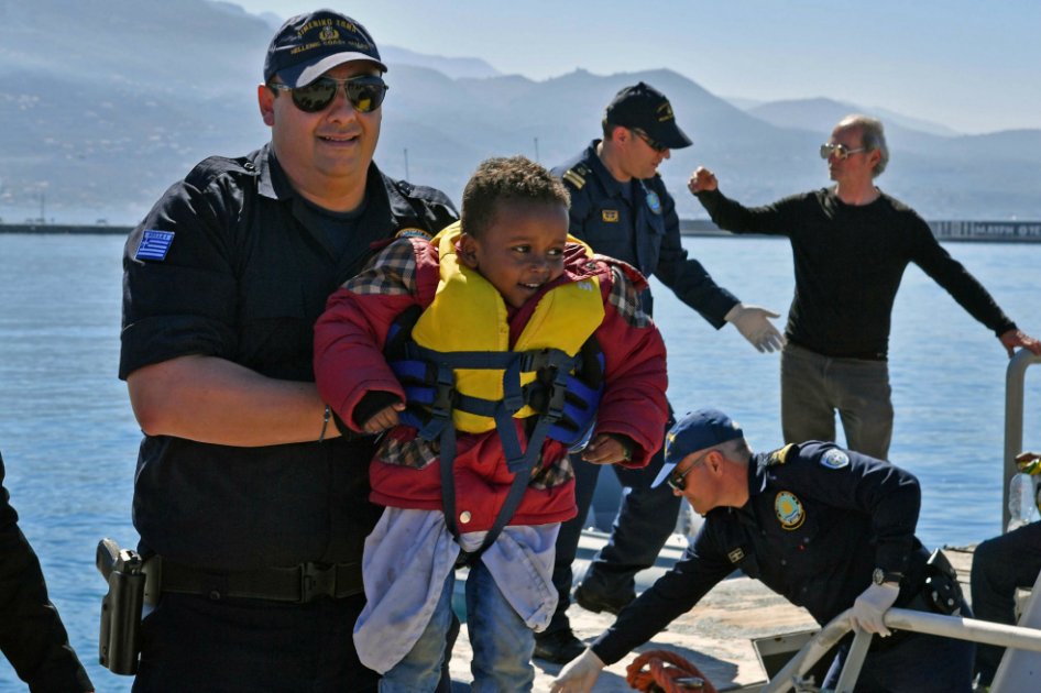 Un guardacostas alza a un niño migrante en el puerto de Kalmata, Grecia. / EFE