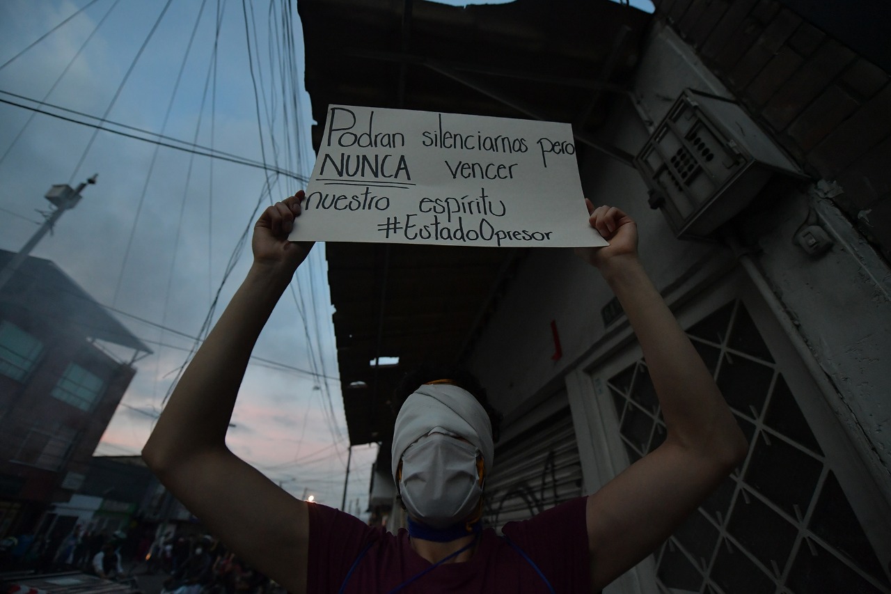 Un hombre encapuchado sostiene un cartel