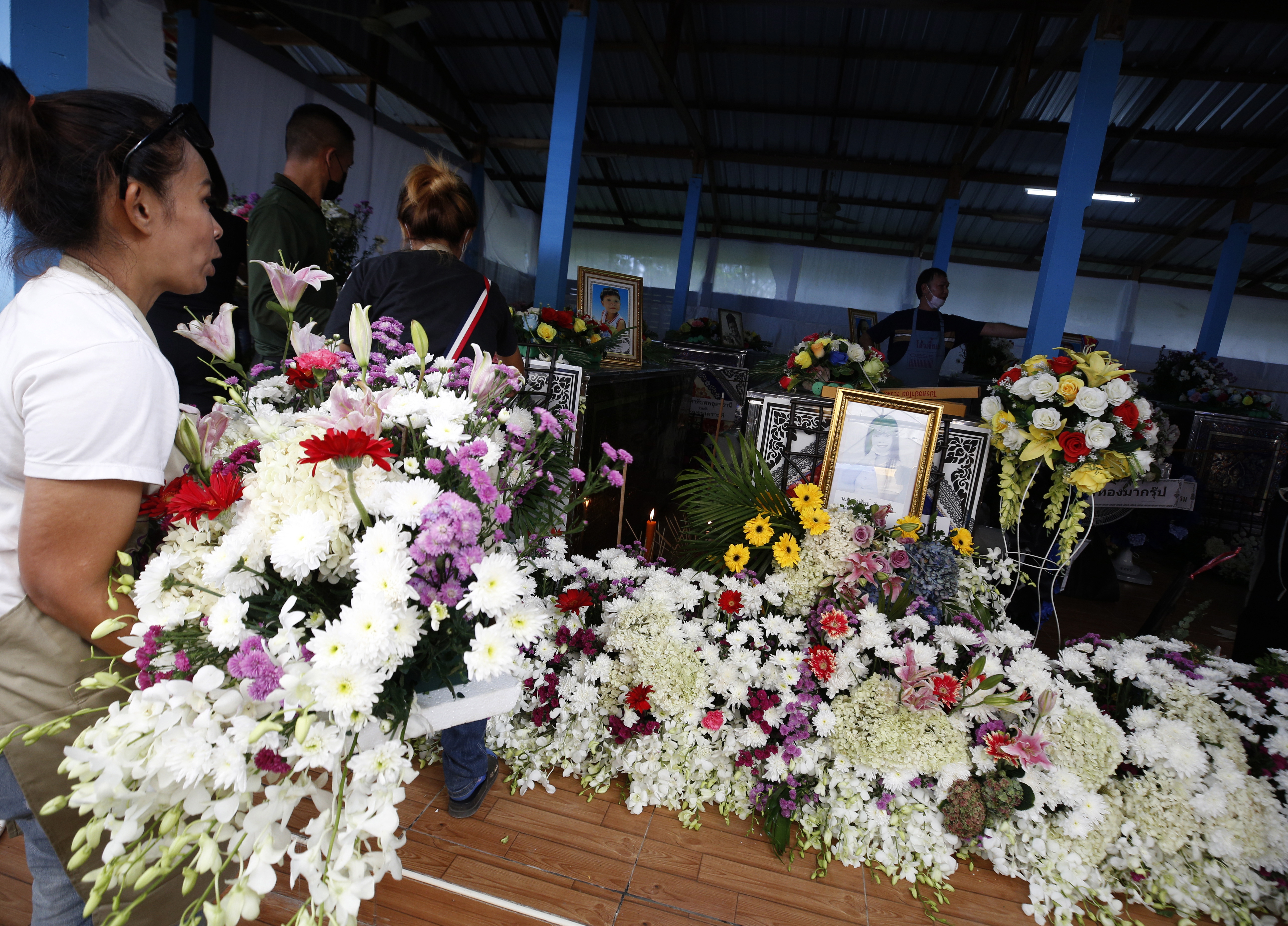 Los lugareños decoran con flores los ataúdes de las víctimas de un tiroteo masivo en un centro de cuidado infantil, antes de la ceremonia religiosa fúnebre en un templo budista en la provincia de Nong Bua Lamphu.