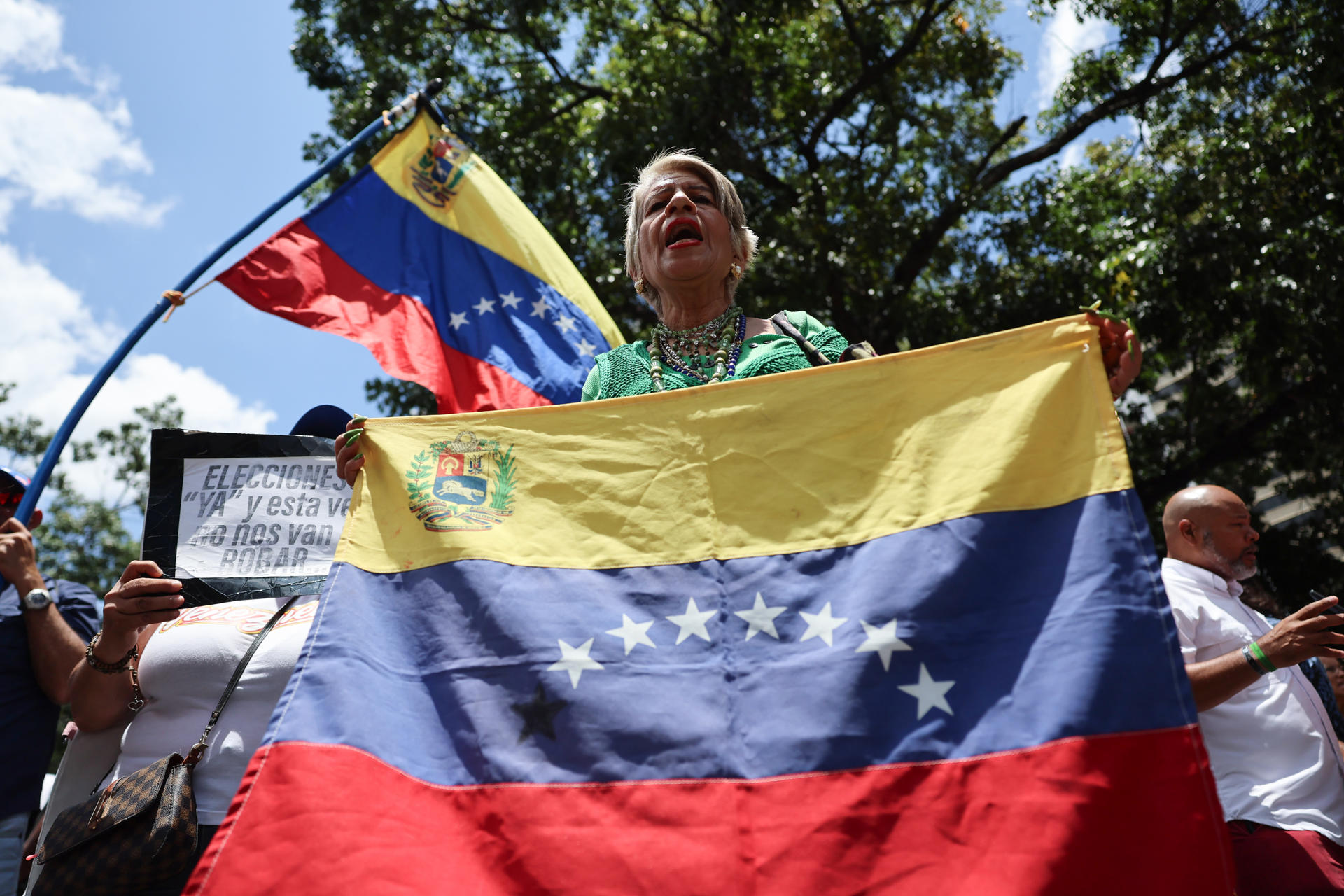 AME8406. CARACAS (VENEZUELA), 12/08/2026.- Una persona sostiene una bandera durante una manifestación este miércoles, mientras la primera ronda de negociación entre el Gobierno y la oposición de Venezuela, promovida por Estados Unidos, ocurre al interior del hotel Meliá Caracas, en Caracas (Venezuela). EFE/ Miguel Gutiérrez
