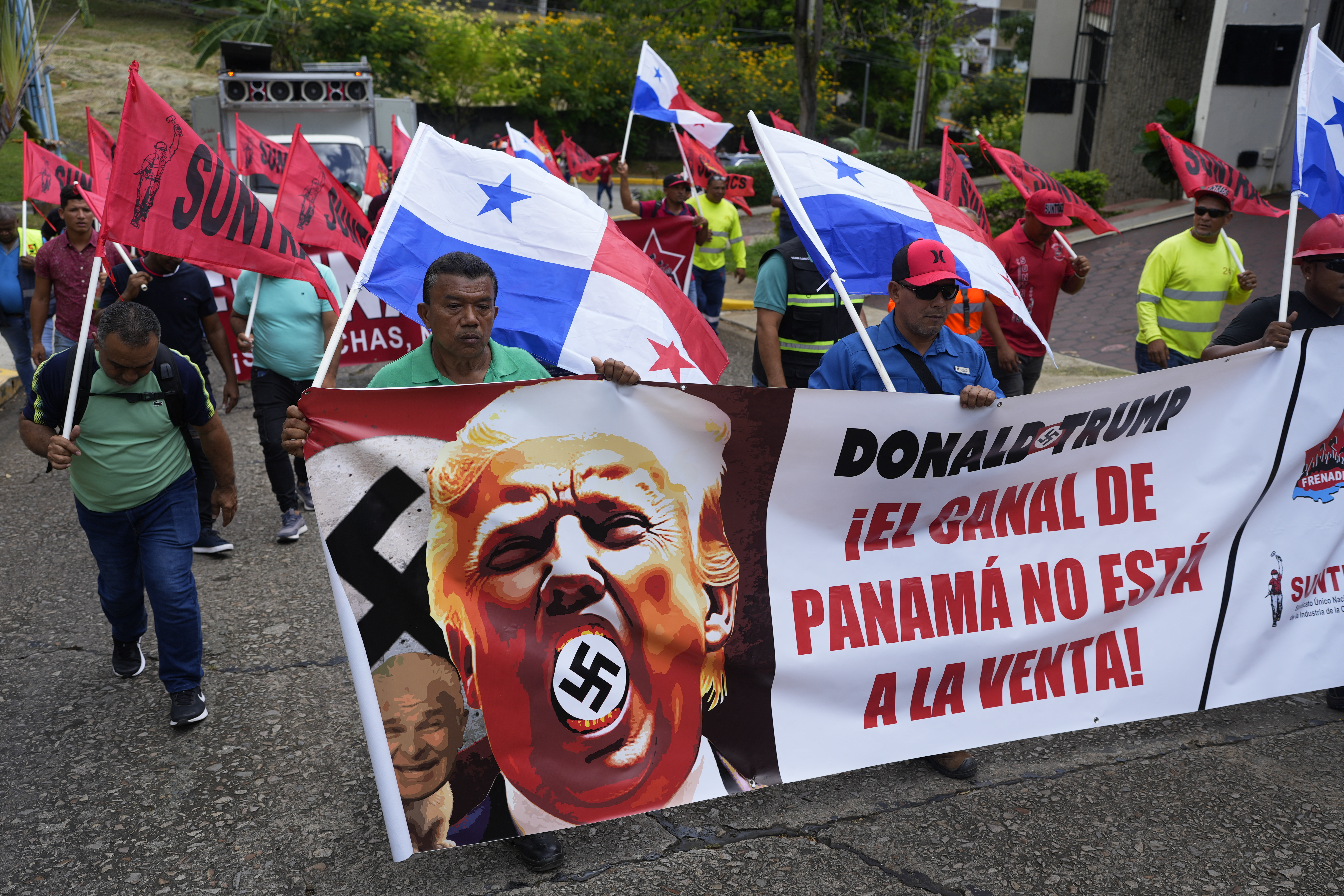 Demonstrators hold a banner reading "The Panama Canal is Not For Sale" with a picture of US President Donald Trump with a swastika during a protest against his inauguration in Panama City outside the residence of the US ambassador in Panama City on January 20, 2025.