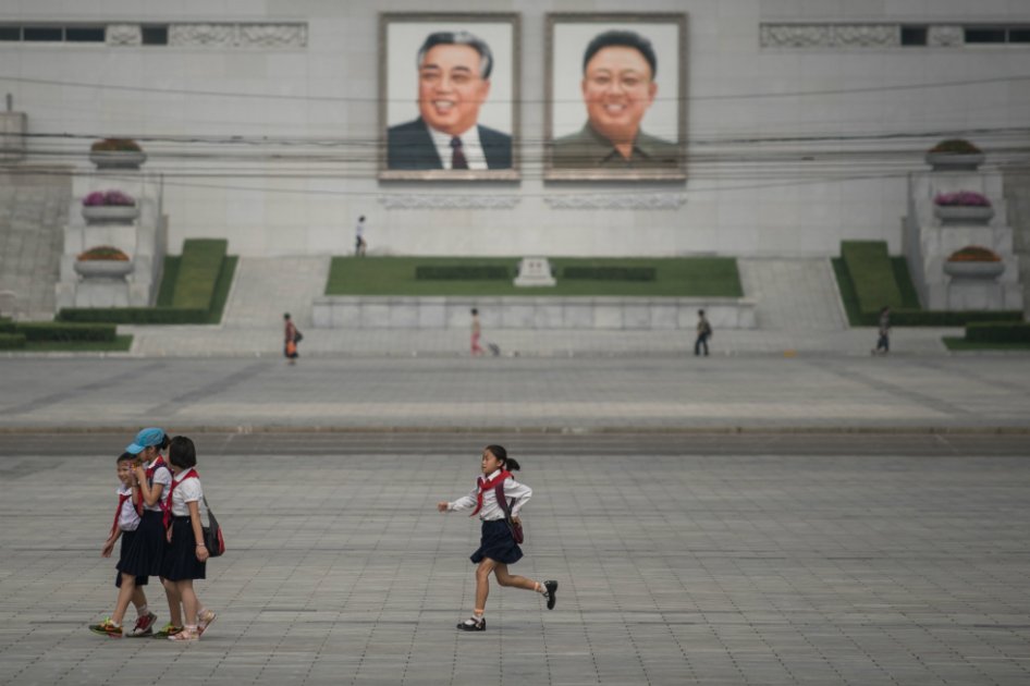 Niños corren delante de los retratos de los ex líderes de Corea del Norte Kim Il-Sung y Kim Jong-Il, en Pyongyang. / AFP