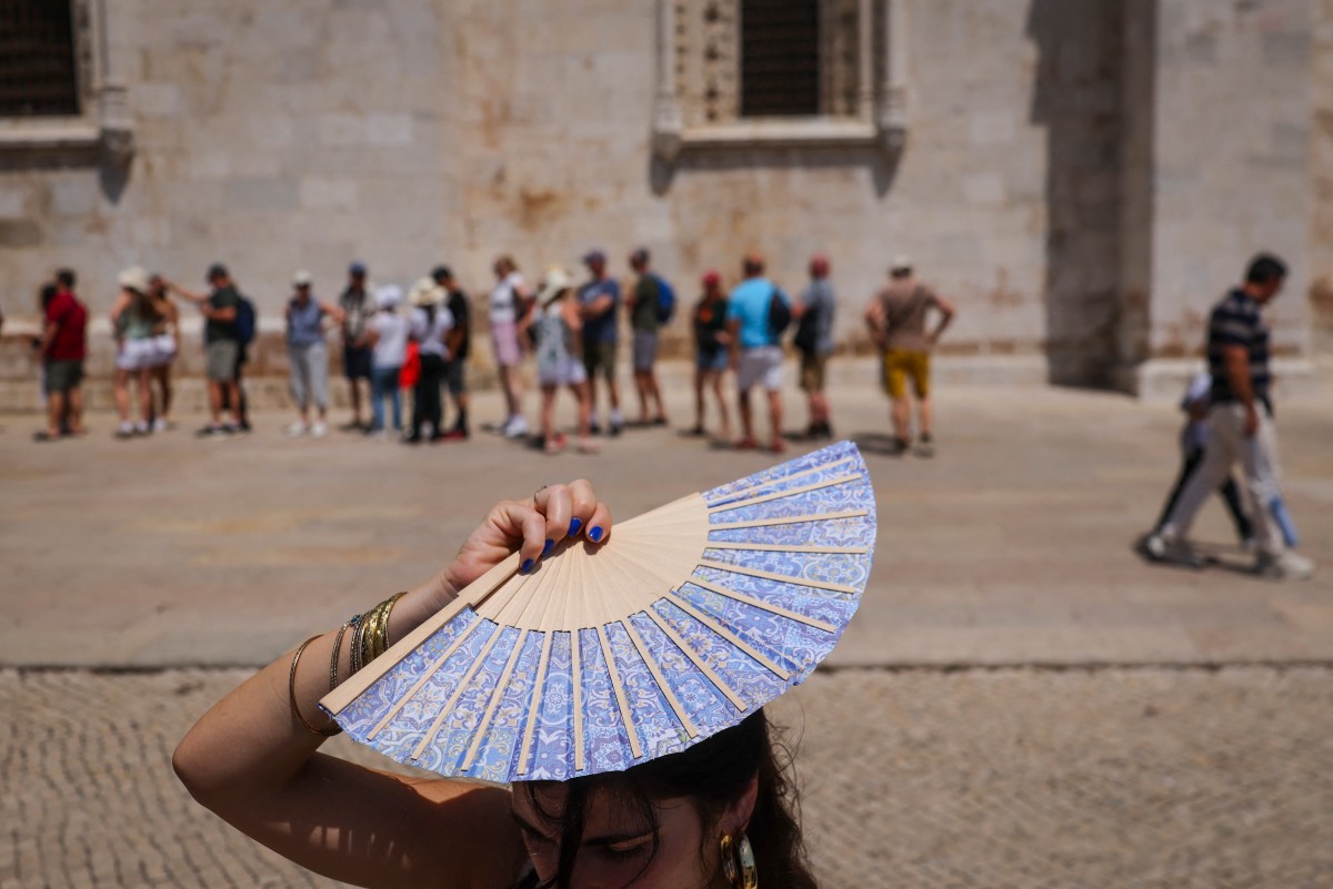 TOPSHOT - A woman shades her head with a fan in front of Jeronimos Monastery in Belem, during a heatwave in Lisbon  on May 27, 2026.