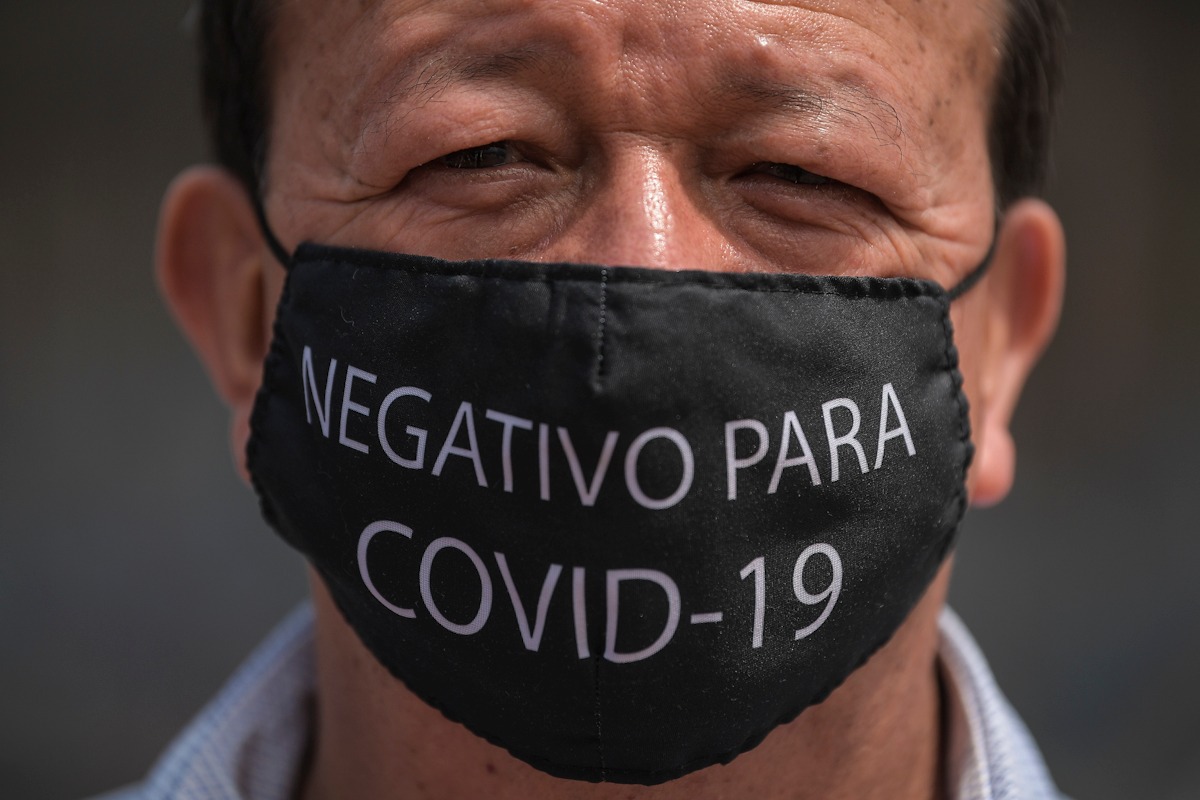 Un hombre con un tapabocas que dice: negativo para covid-19.
