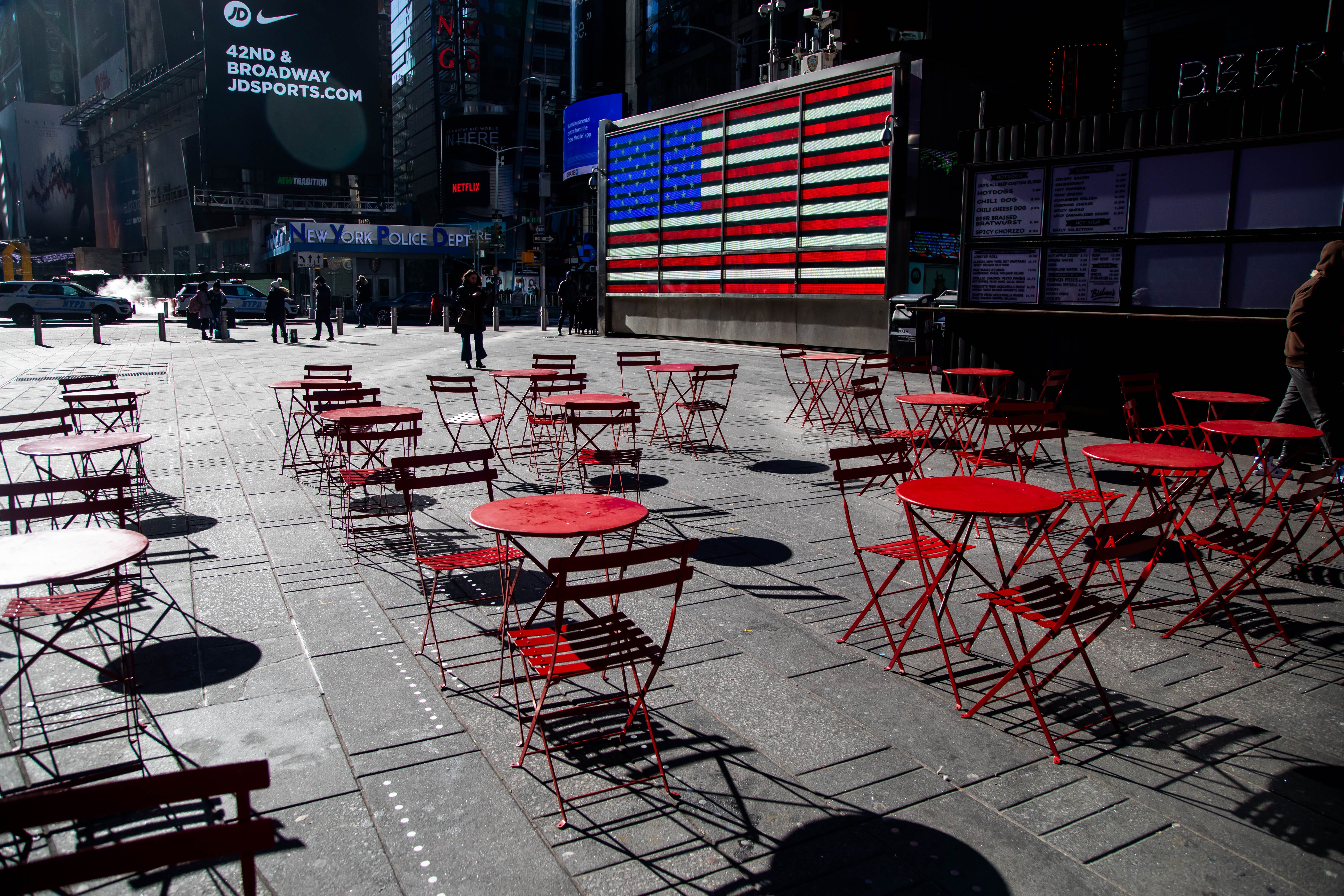 An American flag near empty tables and chairs in the Times Square area of New York, U.S., on Friday, Jan. 21, 2022. With the worst start of a year in more than a decade and a $2.2 trillion wipeout in market value, the Nasdaq Composite Index couldnt have had a messier kickoff to 2022. Photographer: Michael Nagle/Bloomberg