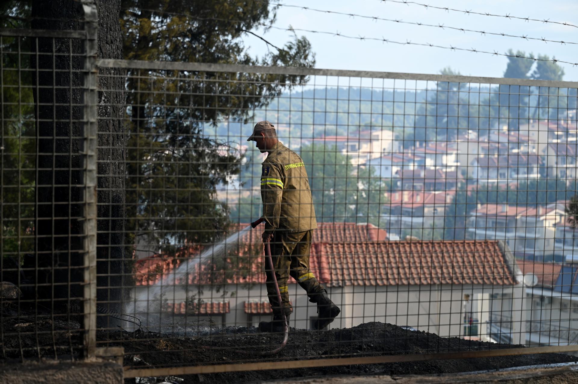 SIVIRI (Greece), 14/08/2026.- A firefighter tries to put out a fire in the yard of a residence in the summer resort of Siviri, Chalkidiki, northern Greece, 14 August 2026. The situation regarding the fire that broke out on 13 August in Siviri, Chalkidiki, has improved; there is no active fire front, although there are many scattered hotspots, according to the Fire Service. Seven to eight houses and several vehicles have sustained serious damage, while the general estimate for the burnt forest area is 4,000 stremmata, according to the local Fire Service commander. (incendio forestal, Grecia) EFE/EPA/STRINGER