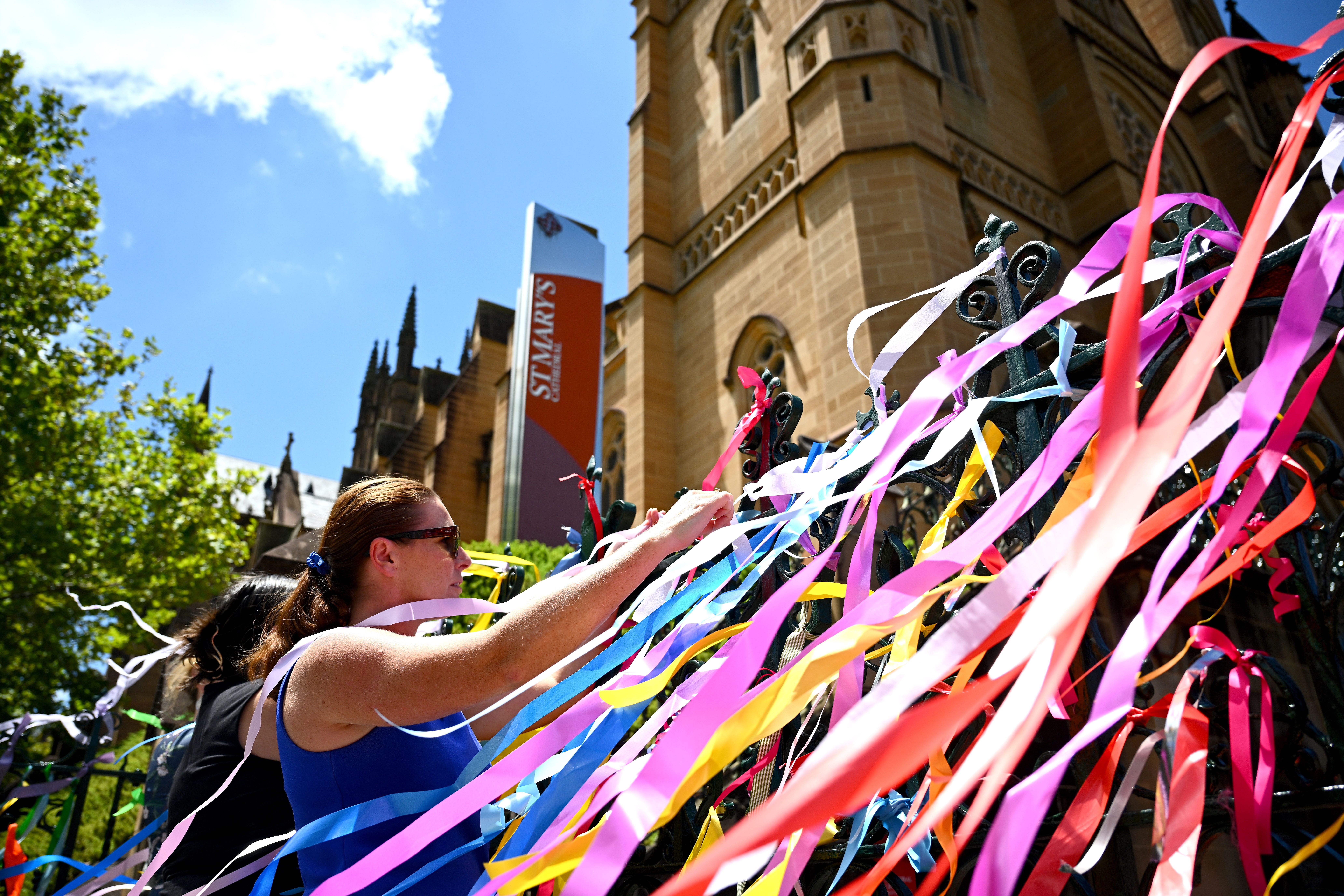 Sydney (Australia), 01/02/2023.- Abuse survivor Karen Iles (R) adjusts a ribbon after tying it to the fence at St Mary's Cathedral in Sydney, Australia, 01 February 2023. Cardinal George Pell's body will lie in state at Sydney's St. Mary's Cathedral before being buried at a private ceremony. EFE/EPA/DAN HIMBRECHTS AUSTRALIA AND NEW ZEALAND OUT