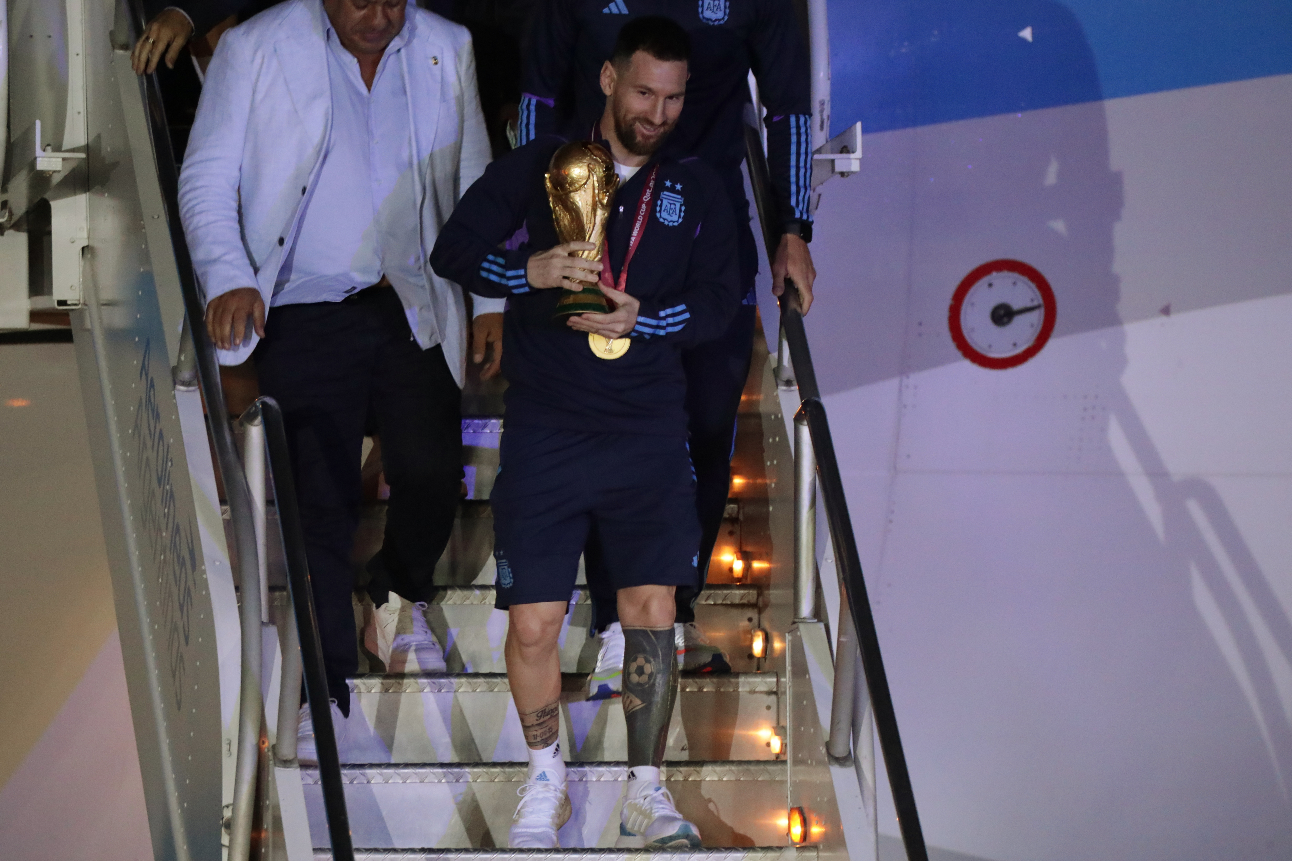 AMDEP9828. EZEIZA (ARGENTINA), 19/12/2022.- Lionel Messi de la selección argentina de fútbol desciende con el trofeo del Mundial de Fútbol Qatar 2022 a su llegada hoy, al Aeropuerto Internacional de Ezeiza a unos 22km de Buenos Aires (Argentina). EFE/ Raúl Martínez