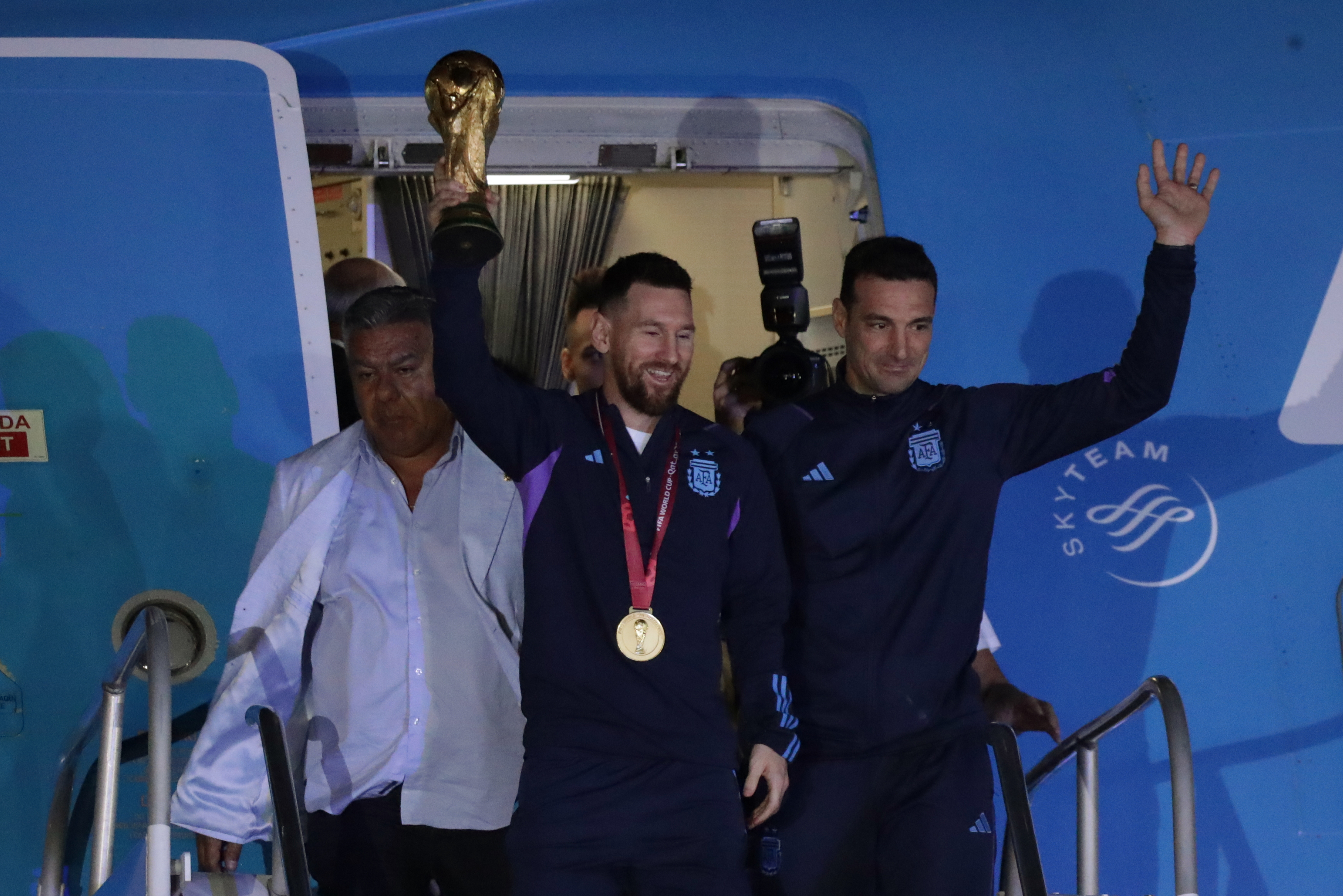 AMDEP9828. EZEIZA (ARGENTINA), 19/12/2022.- Lionel Messi de la selección argentina de fútbol saluda con el trofeo del Mundial de Fútbol Qatar 2022 junto al seleccionador Lionel Scaloni (d) a su llegada hoy, al Aeropuerto Internacional de Ezeiza a unos 22km de Buenos Aires (Argentina). EFE/ Raúl Martínez