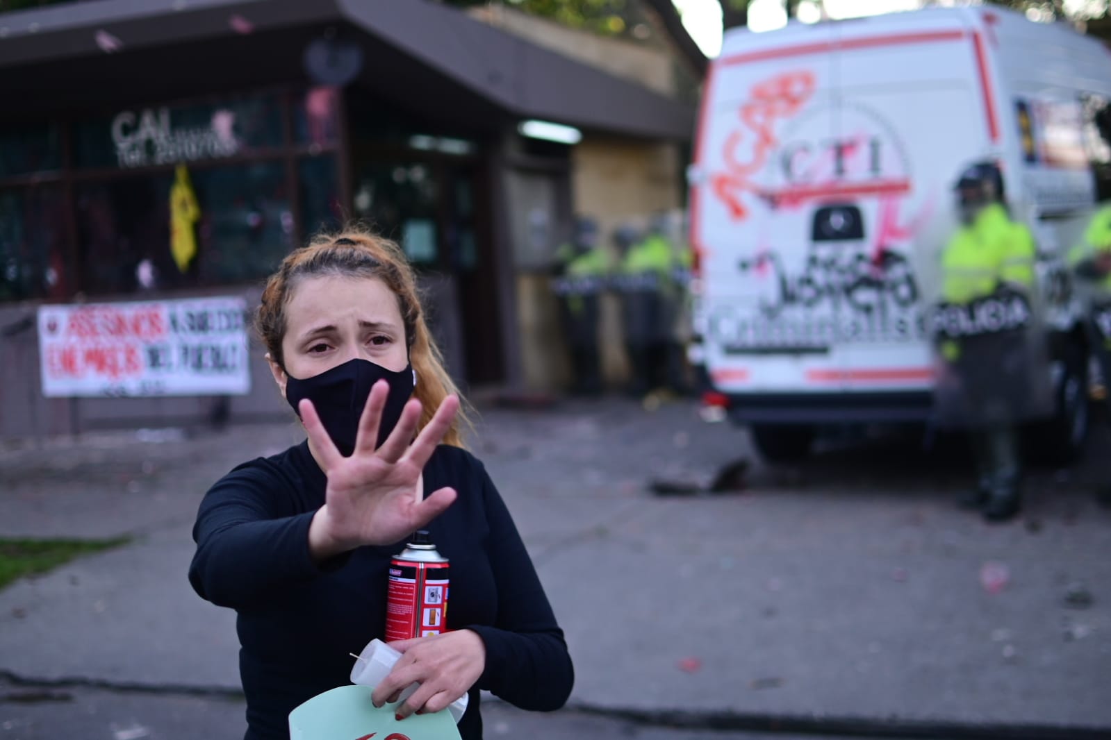 Una mujer con la mano derecha levantada hacia la cámara.