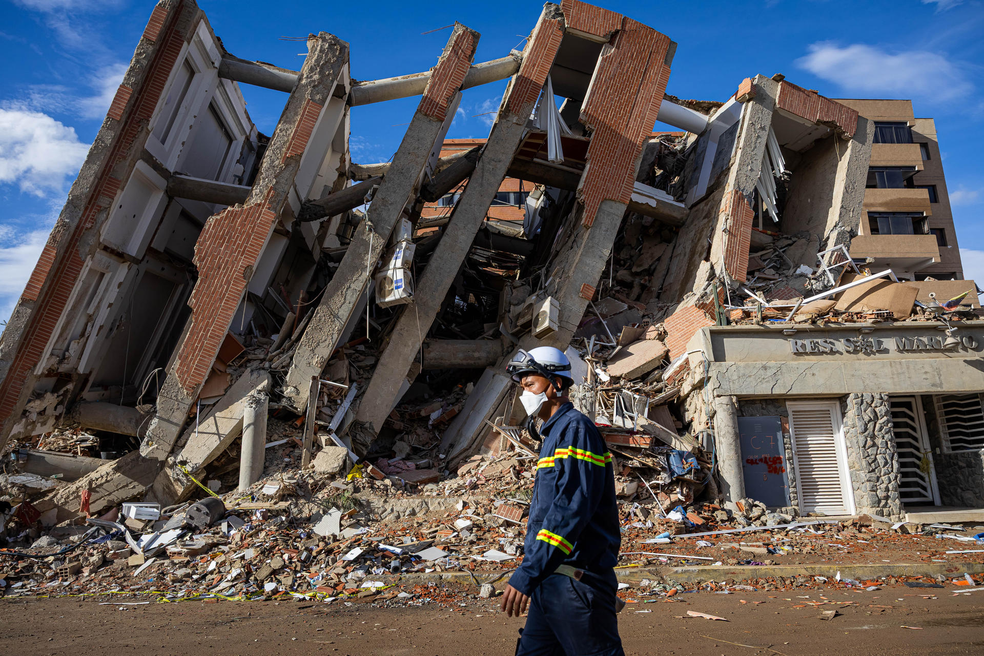 AME6123. LA GUAIRA (VENEZUELA), 30/06/2026.- Un rescatista de Vietnam camina este martes frente a escombros de edificaciones destruidas en Catia La Mar, La Guaira (Venezuela). La cifra de fallecidos por el doble terremoto ocurrido el pasado miércoles en la zona norte de Venezuela ascendió a 1.943 y la de heridos a 10.571, informó el presidente del Parlamento, Jorge Rodríguez. EFE/ Miguel Gutiérrez