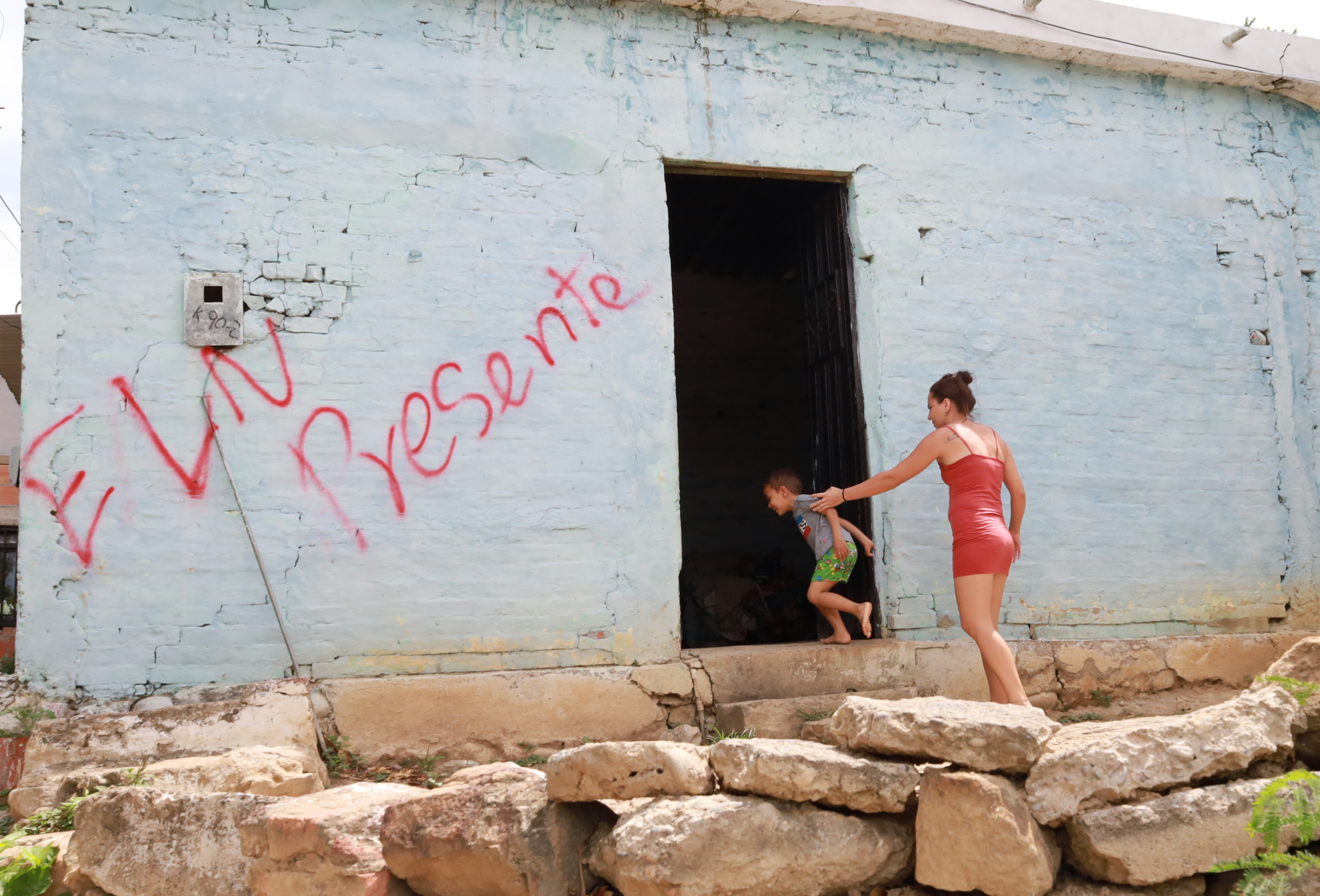 AME1004. CÚCUTA (COLOMBIA), 04/07/2023.- Una mujer y un niño entran a una casa marcada con un grafiti del grupo guerrillero del ELN, hoy, en el barrio Seis de Enero, de la ciudad de Cúcuta (Colombia). El Ejército de Liberación Nacional (ELN) mató este martes a tres policías en el Catatumbo, en el noreste de Colombia, el mismo día que el Comando Central de la guerrilla ordenó a todas sus filas un cese al fuego desde el jueves. Uno de los uniformados, Samir José Vega, falleció en el municipio de Tibú, en el departamento de Norte de Santander (fronterizo con Venezuela), tras recibir un disparo de un francotirador mientras hacía guardia en el sector La Petrolea. Además este martes otros dos policías perdieron la vida en el municipio de El Zulia, que limita con Cúcuta, región fronteriza con Venezuela. EFE/ Mario Caicedo