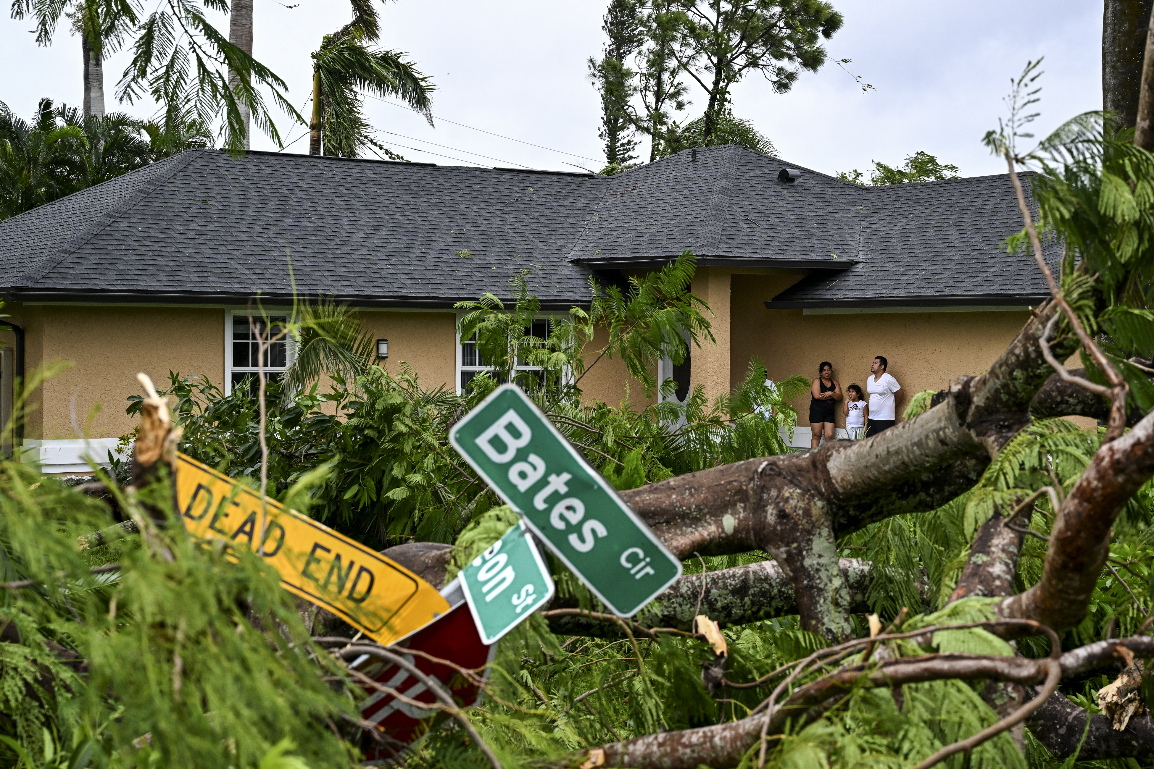 Oscar García (derecha) con su familia se encuentra afuera de su casa después de ser golpeado por un tornado en Fort Myers, Florida, el 9 de octubre de 2024, mientras se acercaba el huracán Milton.