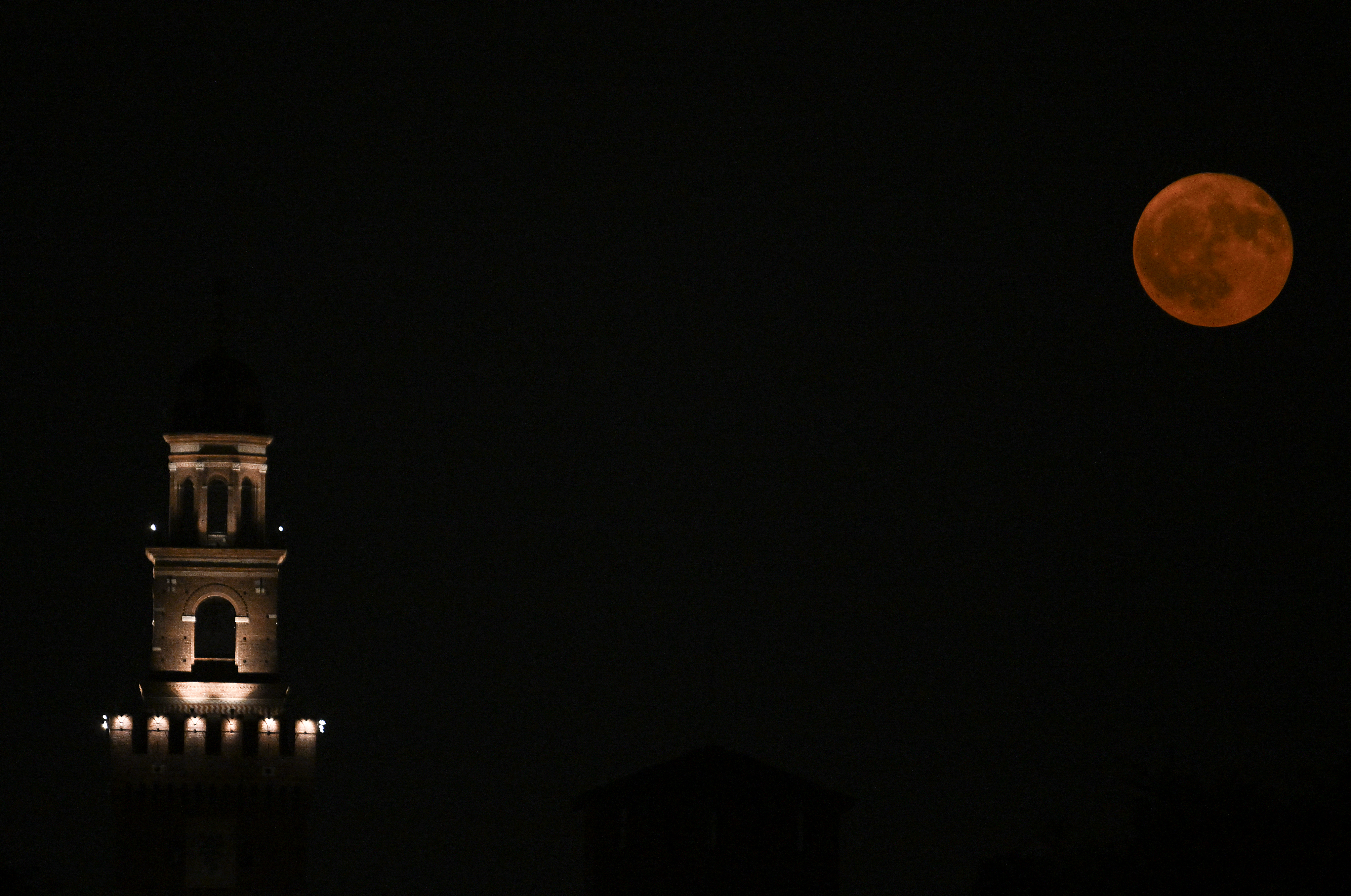 La luna llena, conocida como la “Luna de Fresa”, se eleva sobre la torre del Castillo Sforza en Milán, el 11 de junio de 2025.