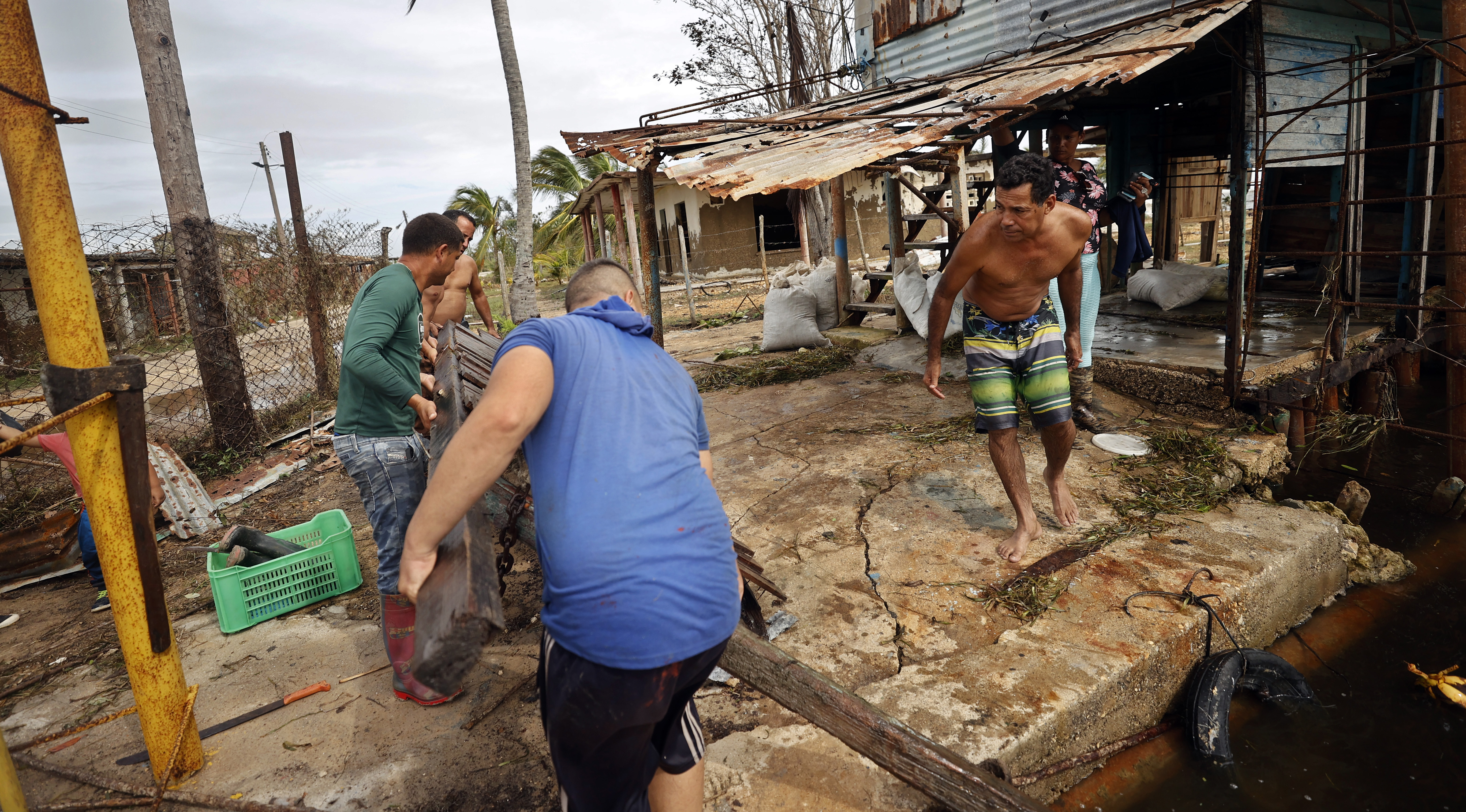 Unas personas recogen escombros tras el paso del huracán Rafael, este jueves en Playa Majana, en la provincia de Artemisa (Cuba). Las afectaciones están concentradas en las provincias occidentales de La Habana, Artemisa y Mayabeque.