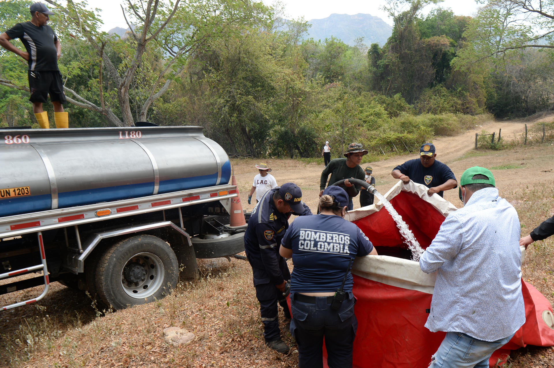 Bomberos y voluntarios llenan un balde de helicóptero para atender uno de los incendios forestales, en Tolima.
