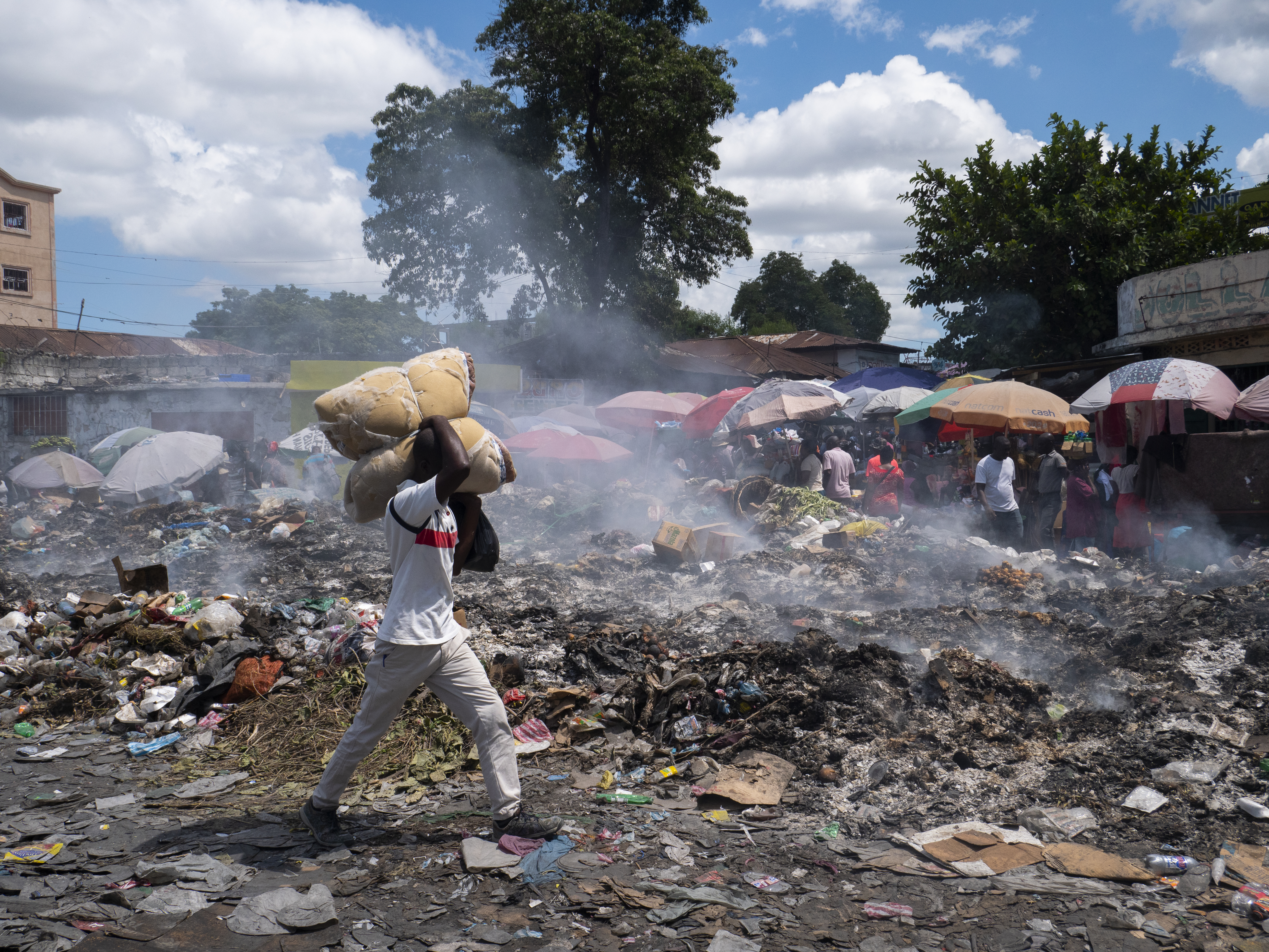 -FOTODELDÍA- AME3017. PUERTO PRÍNCIPE (HAITÍ), 08/10/2022.- Un hombre camina por una calle cubierta de basura que no ha sido recogida, hoy en Puerto Príncipe (Haití) El pedido del Gobierno haitiano a sus socios internacionales para el despliegue "inmediato de una "fuerza armada especializada" dirigida a enfrentar la grave situación del país, es considerado "desestabilizador" por algunos sectores y, presuntamente, resultado de una acción "planificada". Haití está sumido en una grave crisis en todos los órdenes que prácticamente ha paralizado el país, y que se agravó a partir del asesinato, en julio de 2021, del presidente Jovenel Moise. EFE/ Carvens Adelson