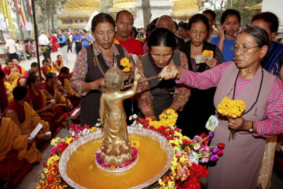 Peregrinas budistas nepalesas ofrecen agua sagrada a una imagen de Buda durante las celebraciones por el 2.555 aniversario del nacimiento de Buda en el templo Syambhu de Katmandú en mayo de 2011