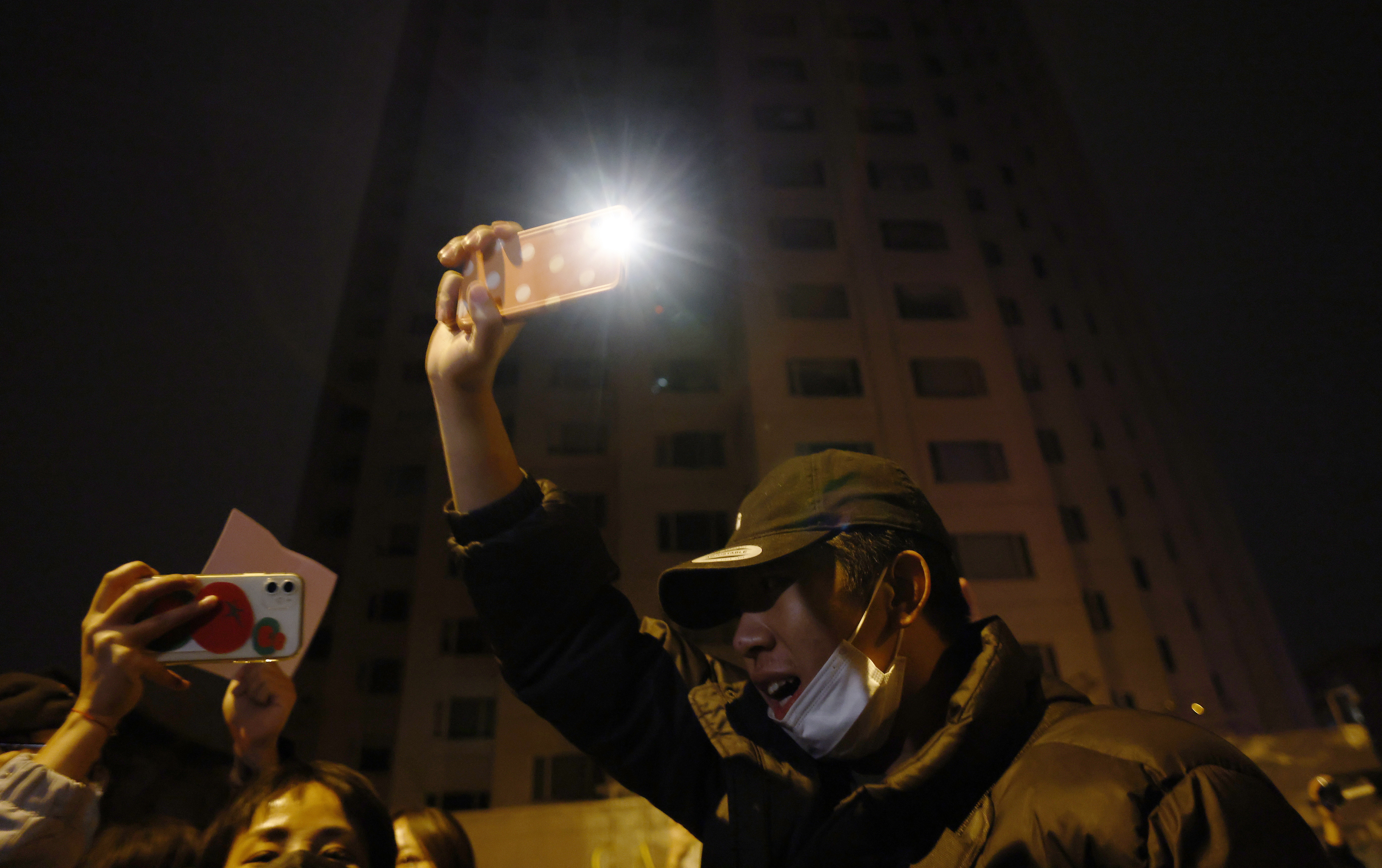 Beijing (China), 27/11/2022.- A protester holds up his lighted mobile phone during a protest triggered by a fire in Urumqi that killed 10 people in Beijing in Beijing, China, 27 November 2022. Protests against'Äôs China strict Covid restrictions have erupted in various cities including Beijing and Shanghai, triggered by a tower fire that killed 10 people Xinjiang'Äôs capital, Urumqi. (Protestas, Incendio) EFE/EPA/MARK R. CRISTINO