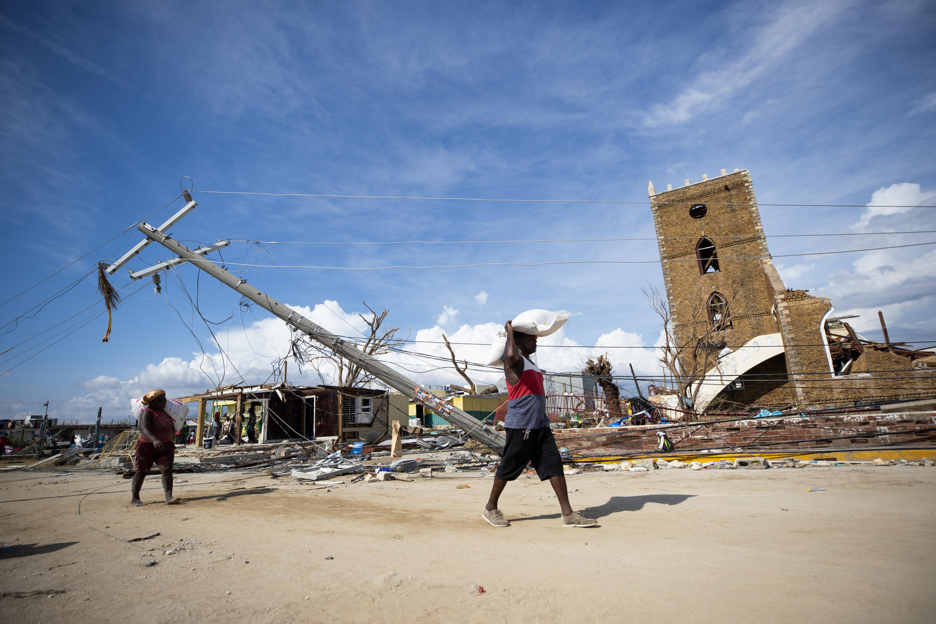 ACOMPAÑA CRÓNICA: JAMAICA HURACANES ATLÁNTICO AME4277. BLACK RIVER (JAMAICA), 01/11/2025.- Personas caminan por una calle destruida por el paso del huracán Melissa este viernes, en Black River (Jamaica). Entre los escombros de la ciudad de Black River, la más afectada en Jamaica por el huracán Melissa, los habitantes enfrentan el caos y los saqueos, mientras tratan de sobrevivir con la ayuda que empieza a llegar a cuentagotas. EFE/ Orlando Barría