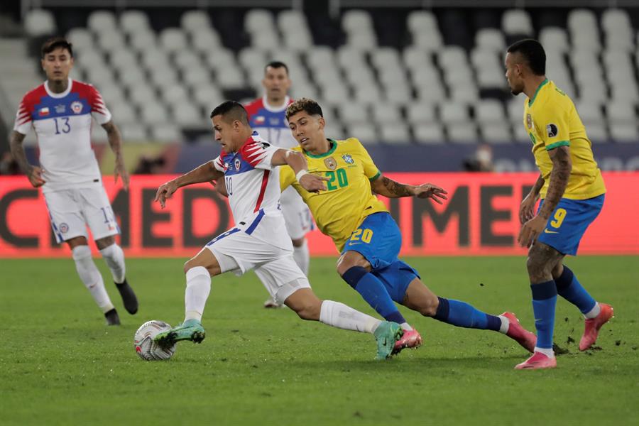 Roberto Firmino disputa la posesión de la pelota con Alexis Sánchez.