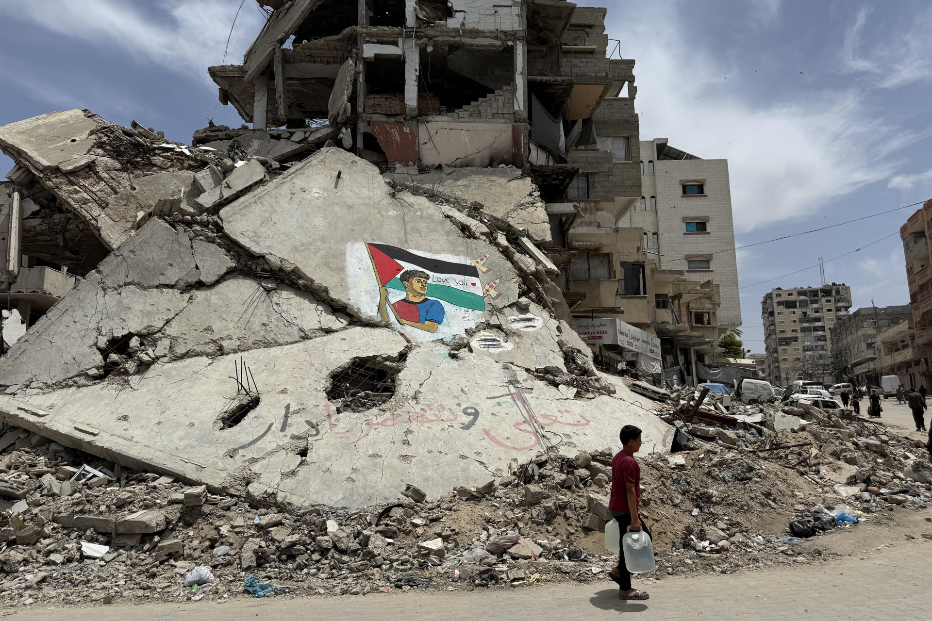 GAZA, 14/05/2026.- Dos artistas palestinos pintaron un mural del futbolista Lamine Yamal sujetando una bandera palestina sobre las ruinas de una casa destruida por ataques israelíes en el campamento de refugiados de Al Shati, al oeste de la ciudad de Gaza. "Derrotaron a Israel y también al Real Madrid. Y para nosotros, es un orgullo ser seguidores del Barcelona", dice a EFE el gazatí Amir Badah, de 18 años, frente a este mural. En el dibujo se ve al culé, alzando la bandera como hizo el lunes durante la rúa de los jugadores del Barça tras ganar la Liga, y en sobre la franja blanca de la enseña palestina hay escrito un "Love you" ('te queremos'), con un corazón rojo. EFE/Ahmad Awad
