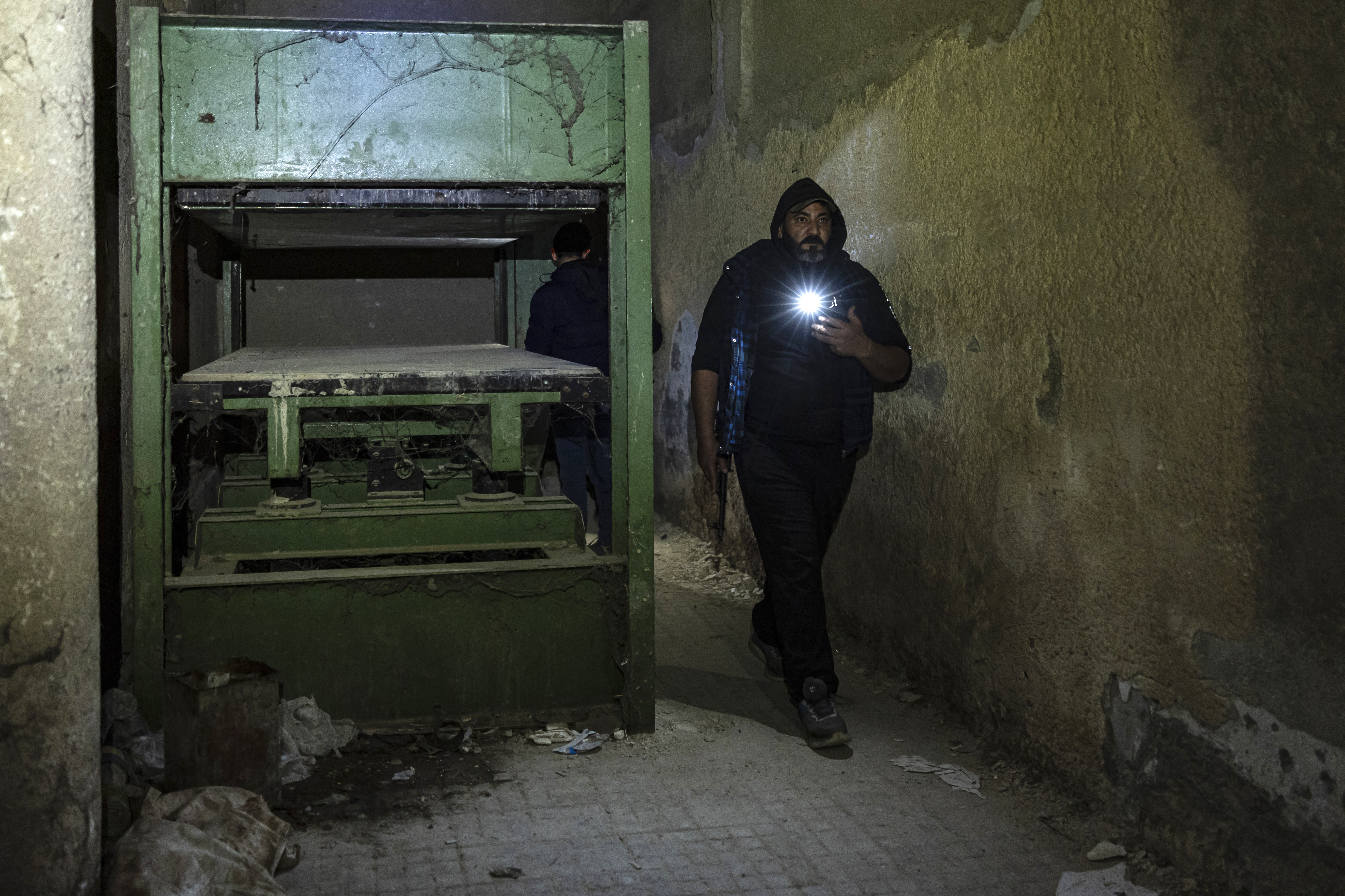 Un hombre armado pasa junto a una prensa mecánica en la prisión de Saydnaya, en Damasco, el 11 de diciembre de 2024.
