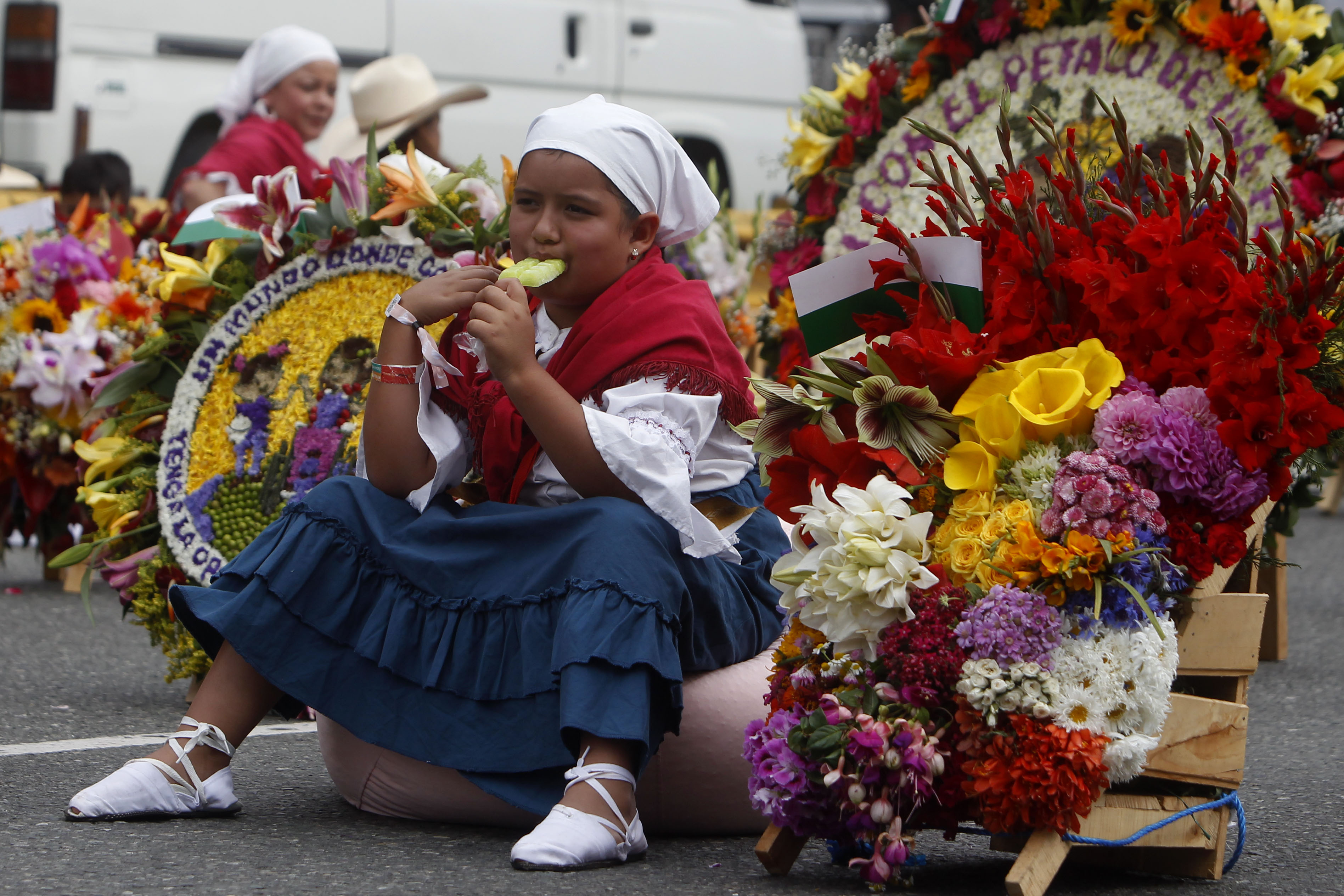 AME8859. MEDELLÍN (COLOMBIA), 07/08/2023.- Una niña silletera come helado antes de la edición 66 del Desfile de Silleteros de la Feria de las Flores hoy, en Medellín (Colombia). Más de medio centenar de silleteros salieron este lunes de sus pintorescas fincas en el caserío de Santa Elena, donde nació hace 66 años esta tradición, para desfilar sus majestuoso arreglos florales y convertir a Medellín en un jardín como gran cierre de la Feria de las Flores. EFE/ Luis Eduardo Noriega A.