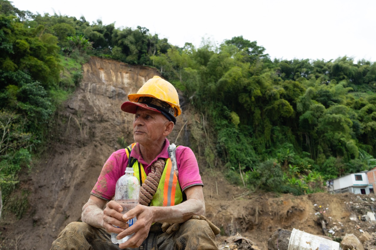 Un hombre sentado con una botella de agua en su manos mira a su derecha