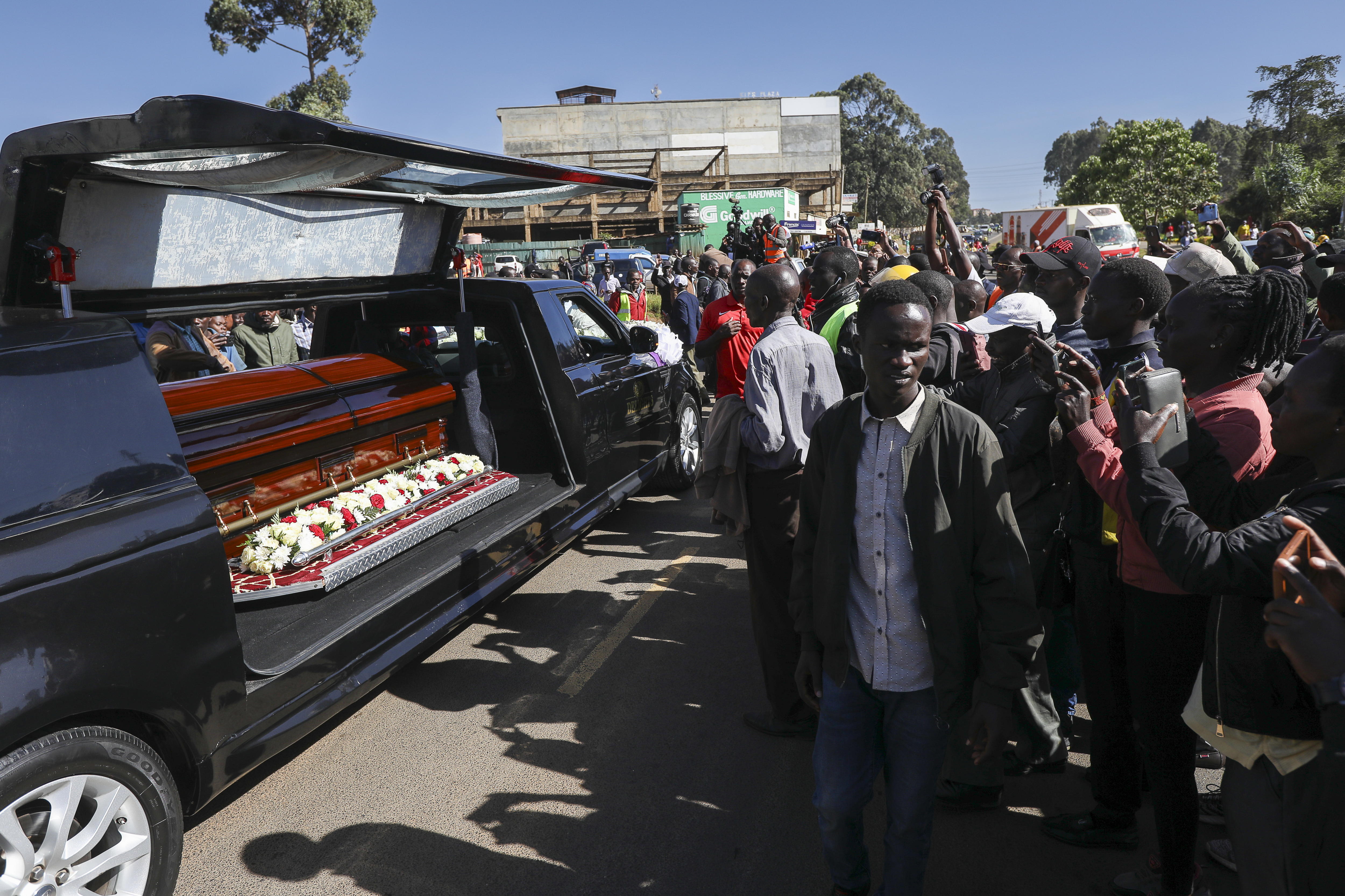Eldoret, (Kenya), 22/02/2024.- People walk along with the hearse carrying the coffin of late Kenyan marathon runner Kelvin Kiptum and take pictures during his funeral proceedings in Eldoret, Kenya, 22 February 2024. Kiptum, who died in a car crash late 11 February 2024 alongside his Rwandan coach Gervais Hakizimana, will be buried on 23 February 2024. Kiptum set a new world record of 2:00.35 at the Chicago Marathon in October 2023. (Maratón, Kenia, Ruanda) EFE/EPA/Daniel Irungu
