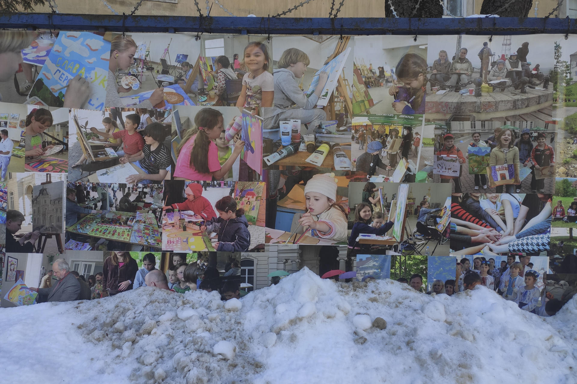 LEÓPOLIS (UCRANIA), 19/01/2026.- Fotografías este lunes de niños ucranianos, colocadas en el muro que rodea el hospital militar de Leópolis (Ucrania), parcialmente cubierto de nieve. Las familias ucranianas con niños pequeños luchan contra los continuos cortes de electricidad y calefacción en medio de un frío intenso, mientras tratan de proteger a los más vulnerables del impacto acumulado de los ataques rusos. EFE/ Rostyslav Averchuk
