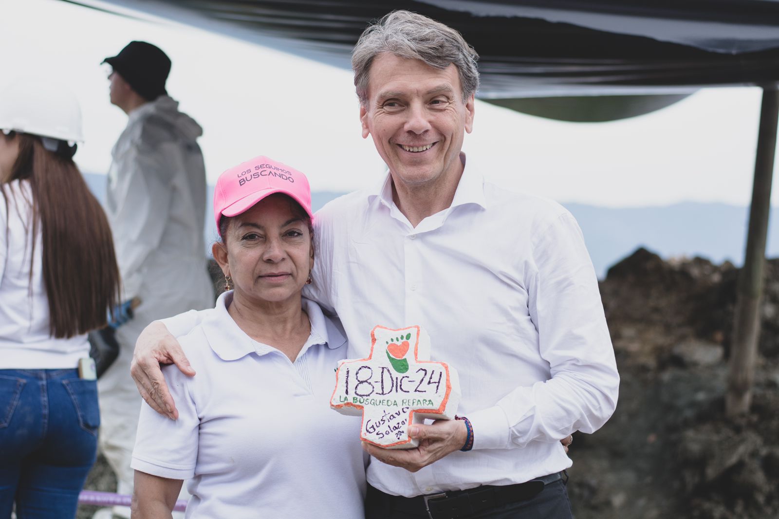 Luz Elena Galeano, quien busca a su esposo Luis Javier Laverde (desaparecido el 9 de diciembre del 2008) y Gustavo Adolfo Salazar, magistrado de la JEP y relator de las medidas cautelares para La Escombrera. Juntos llevan el adoquín en forma de cruz, encontrado en el mismo lugar que había restos humanos, y que marcaron con la fecha del hallazgo forense.