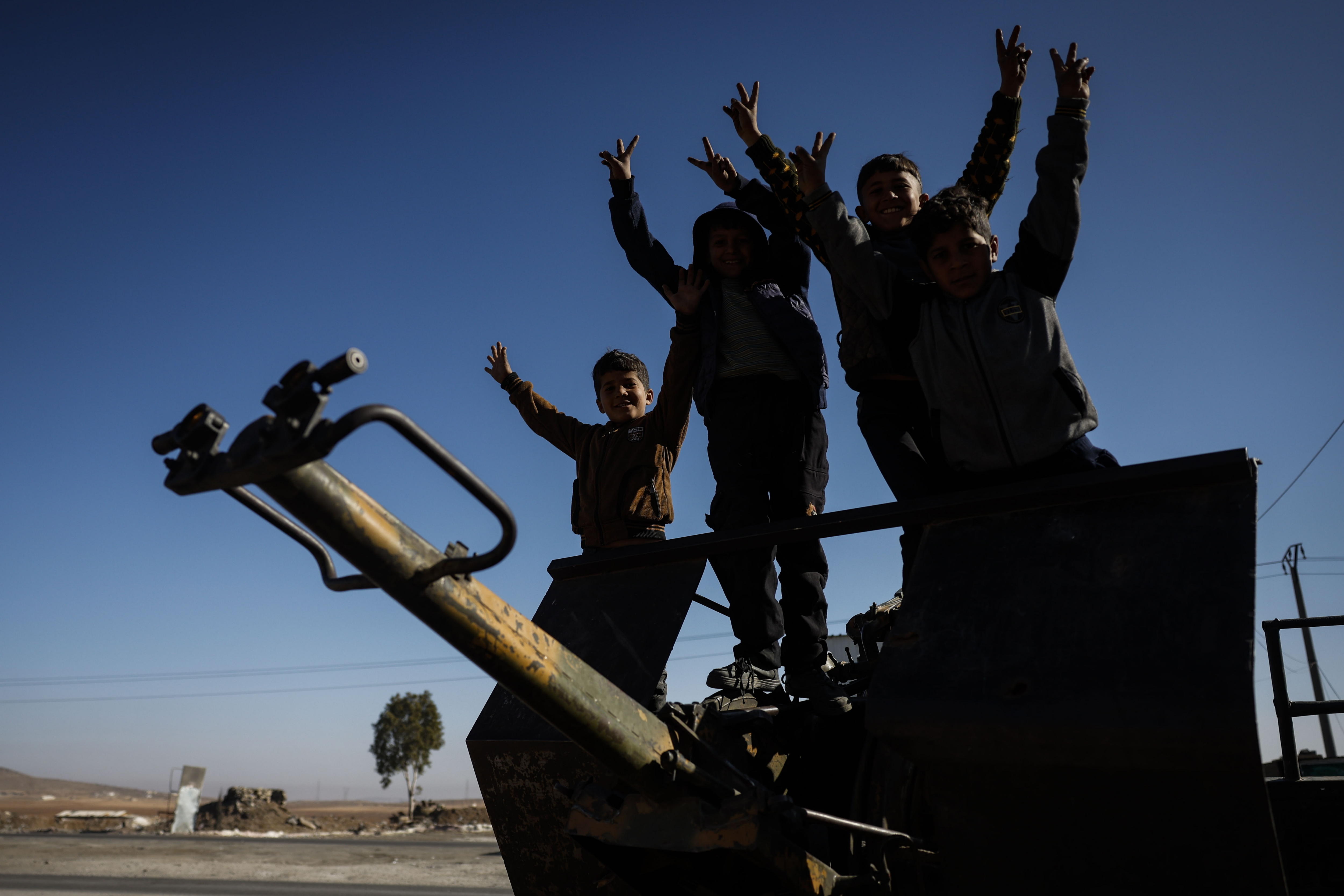 EA2119. DARAA (SIRIA), 17/12/2024.- Un grupo de niños celebra junto a un puesto de control este martes, en Daraa (Siria). Los residentes del sur de Siria han expresado su temor a las incursiones militares israelíes desde la caída del régimen de Bashar al Assad, en una extensa región custodiada en su mayoría por milicias civiles. EFE/EPA/Antonio Pedro Santos