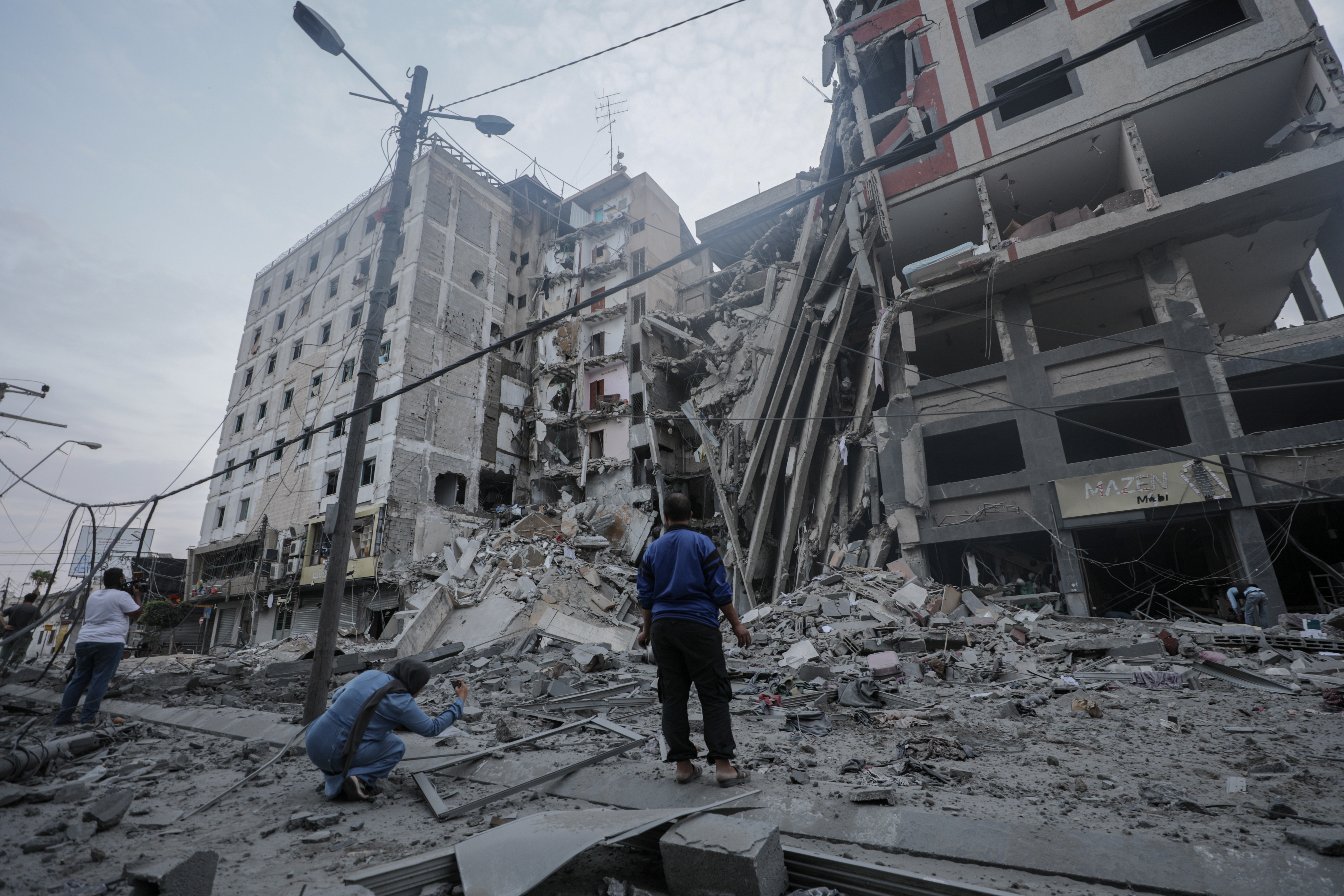 Gaza City (-), 08/10/2023.- Palsetinians inspect the damage in the surrounding of the destroyed National Bank building following Israeli air strikes, in Gaza City, 08 October 2023. The air strikes in retaliation for the 07 October Hamas rocket attacks on Israel, have killed over 300 people in the Gaza Strip, with almost 2,000 wounded, according to Palestinian official sources. EFE/EPA/HAITHAM IMAD