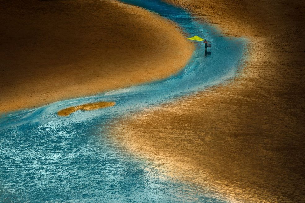 Premio a la Conexión Humana y Océano: Zhang Xiang fue el ganador. En su imagen se observa a un pescador tradicional chino recorriendo la playa mientras la neblina dorada del atardecer se refleja en la arena y el agua.